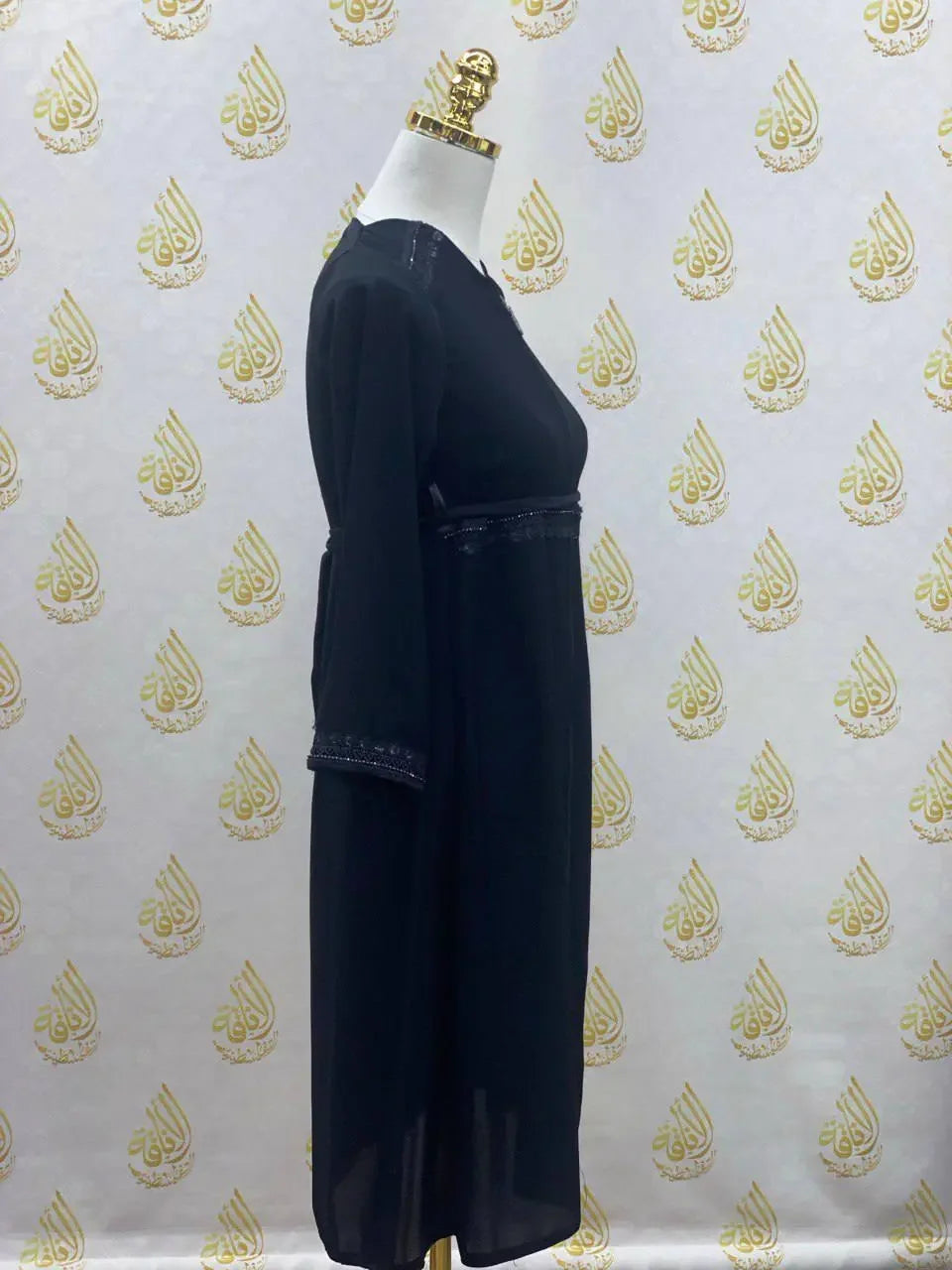 Black kids abaya with zipper by Palestinian Elegance featuring long sleeves and decorative trim