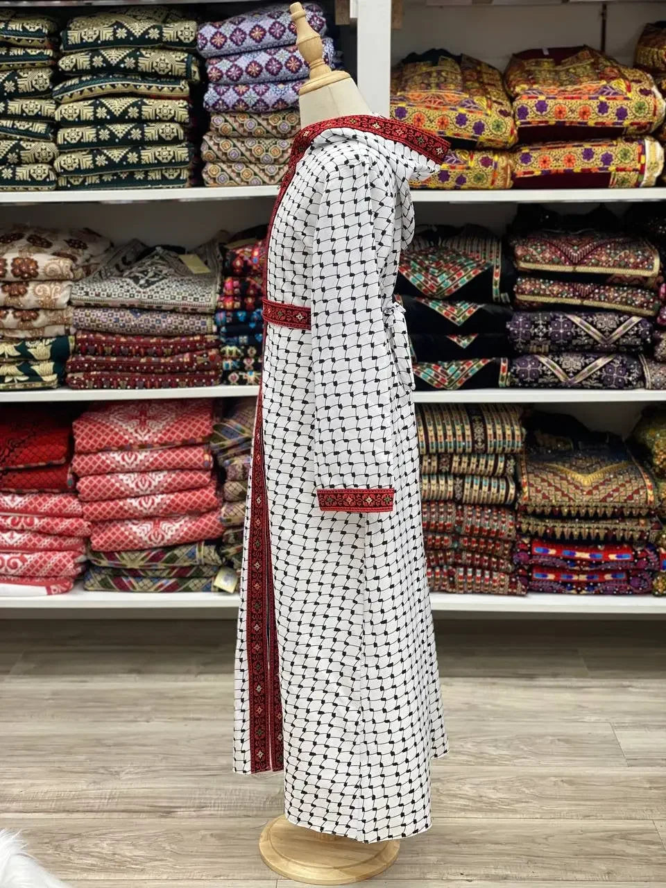 Kids embroidered bisht white with black pattern and red embroidered trim displayed in store