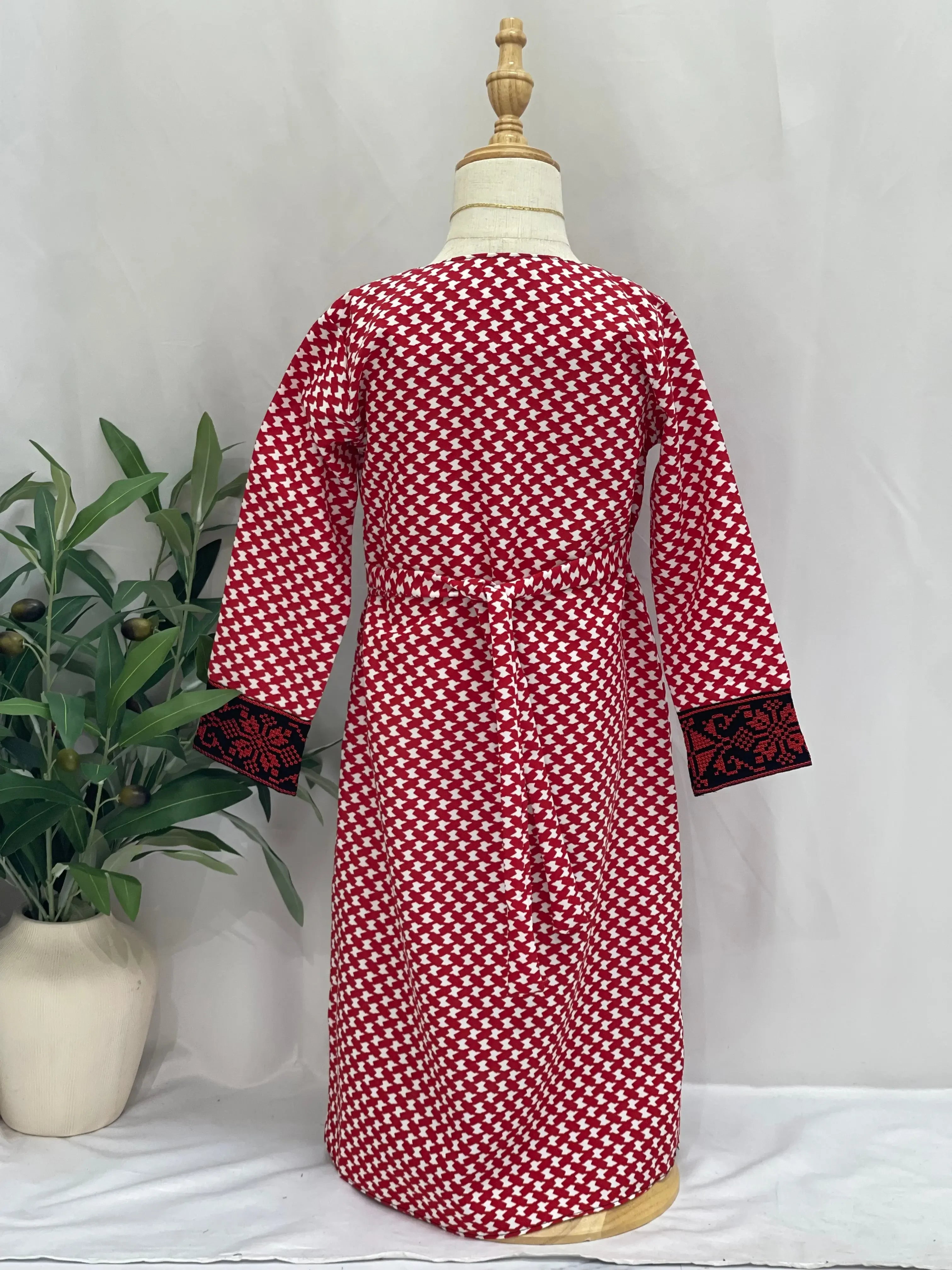 Back view of kids embroidered Palestinian dress in red and white pattern with black embroidered cuffs