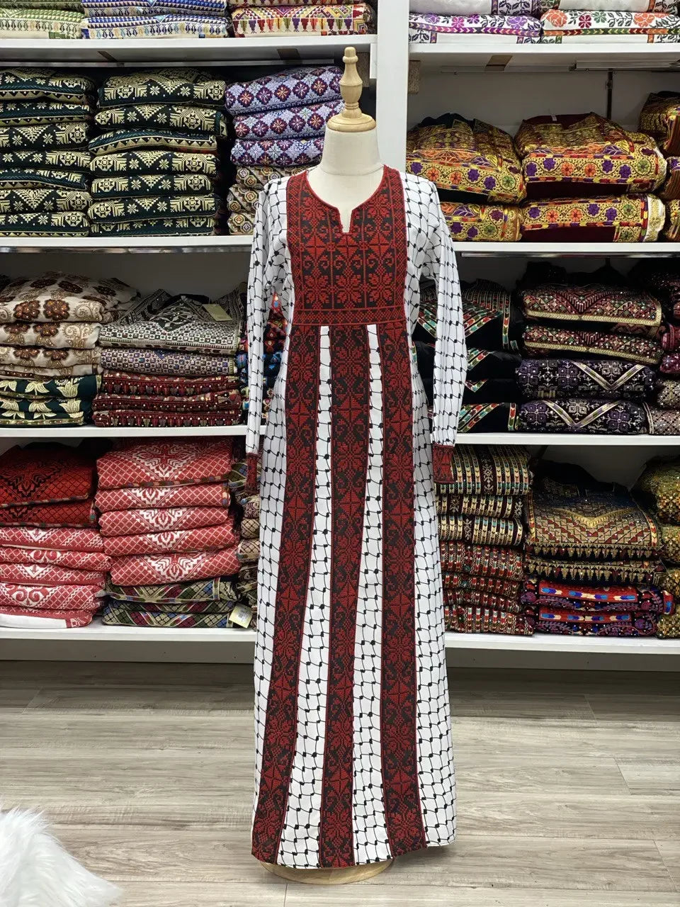 Kids embroidered Palestinian dress in red and white with traditional patterns displayed on a mannequin