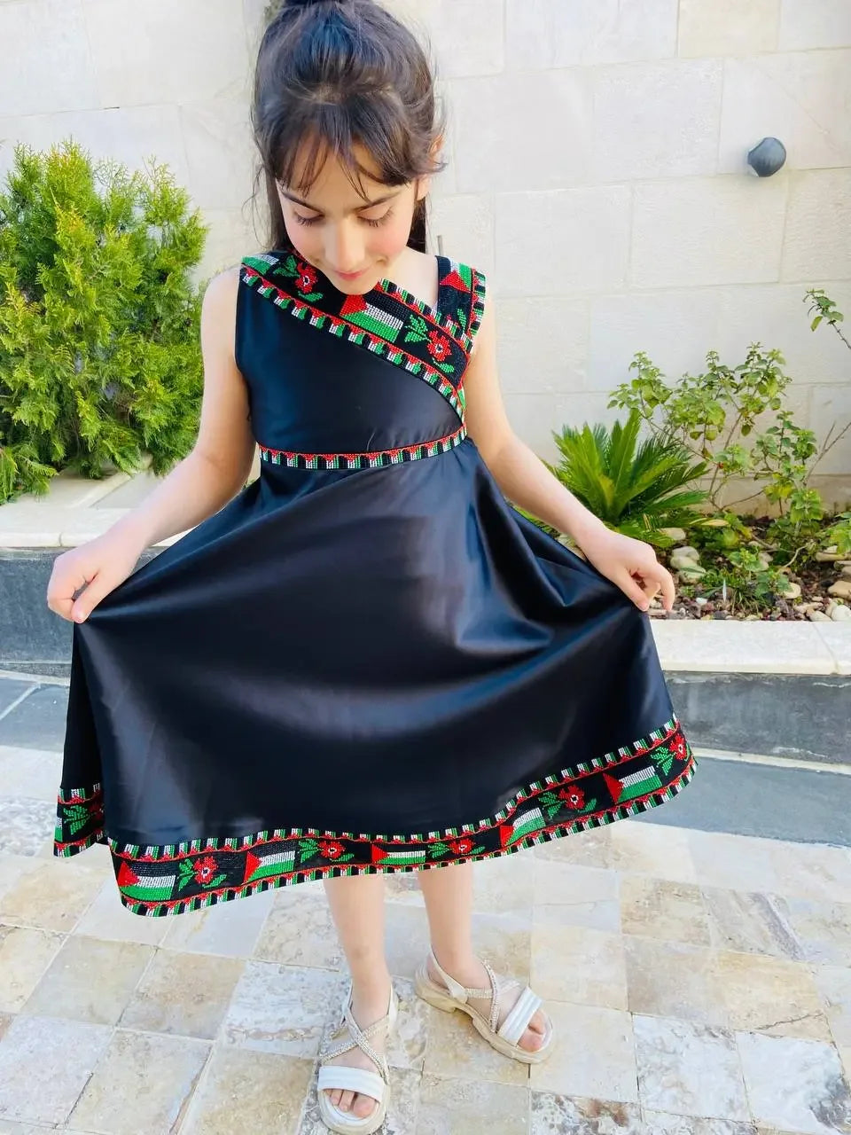 Young girl wearing a black kids Palestine dress with traditional embroidered patterns by Palestinian Elegance