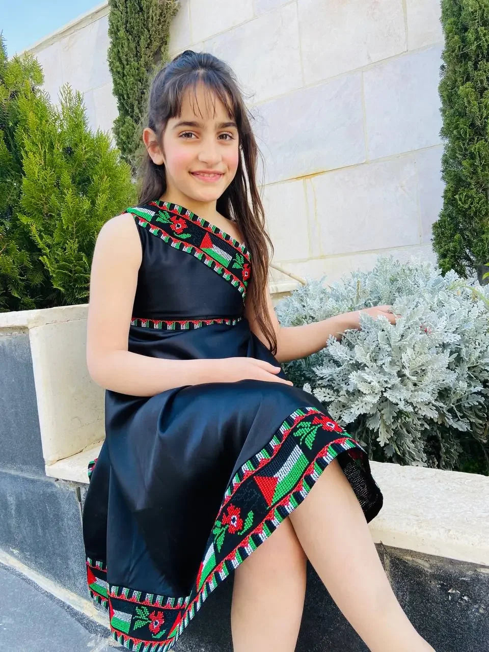 Young girl wearing a black embroidered kids Palestine dress with traditional Palestinian patterns