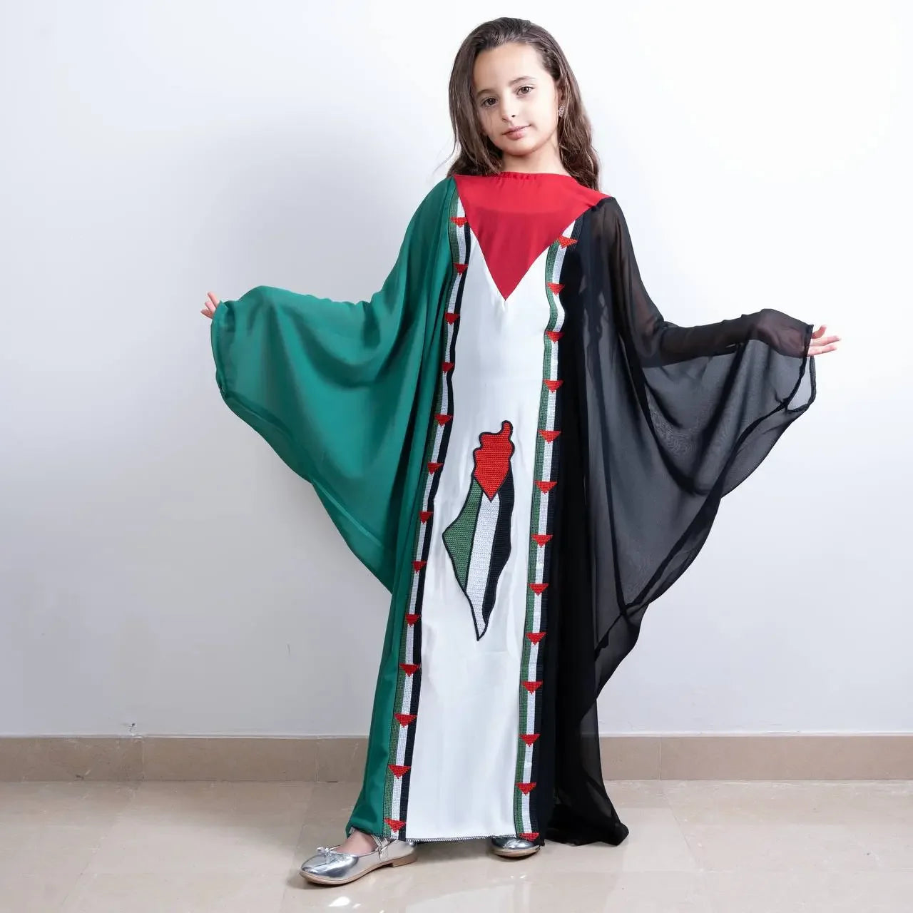 Girl wearing a kids Palestinian flag dress with green, black, red, and white colors from Palestinian Elegance