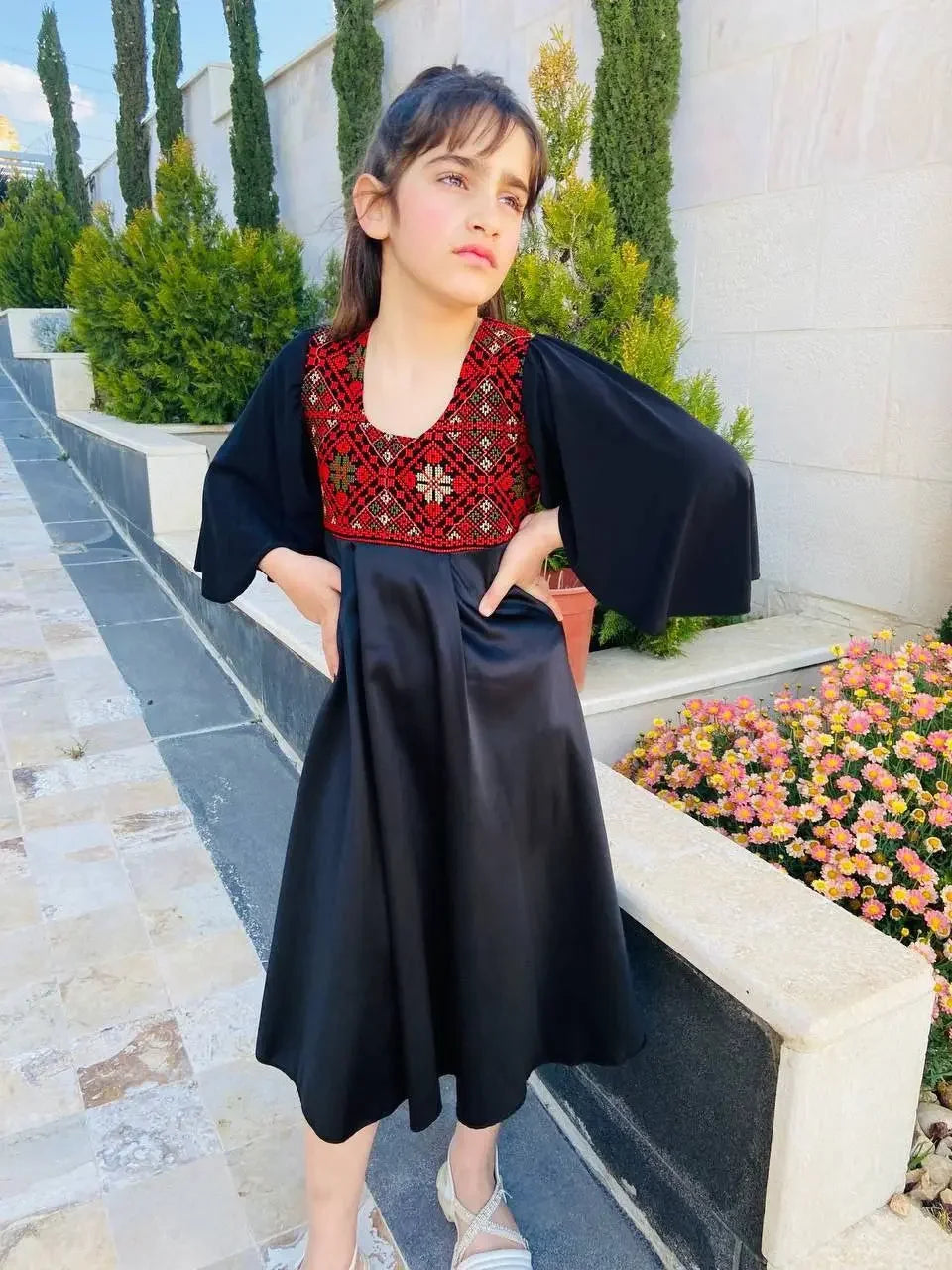 Palestinian Elegance kids tatreez dress with traditional red embroidery on black fabric worn by a young girl