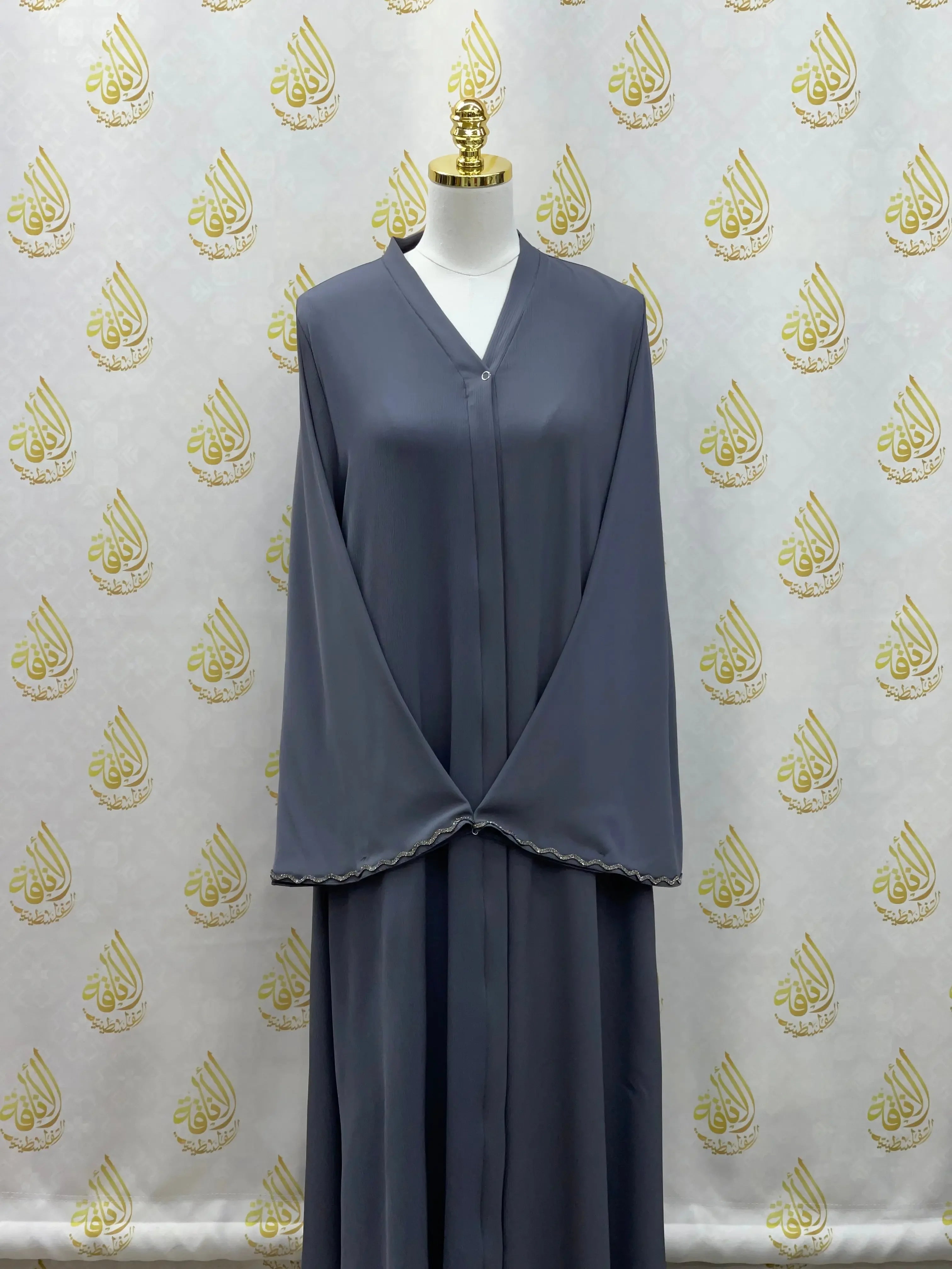 Palestinian Elegance luxurious cloche cut abaya in gray displayed on a mannequin with scalloped sleeve edges