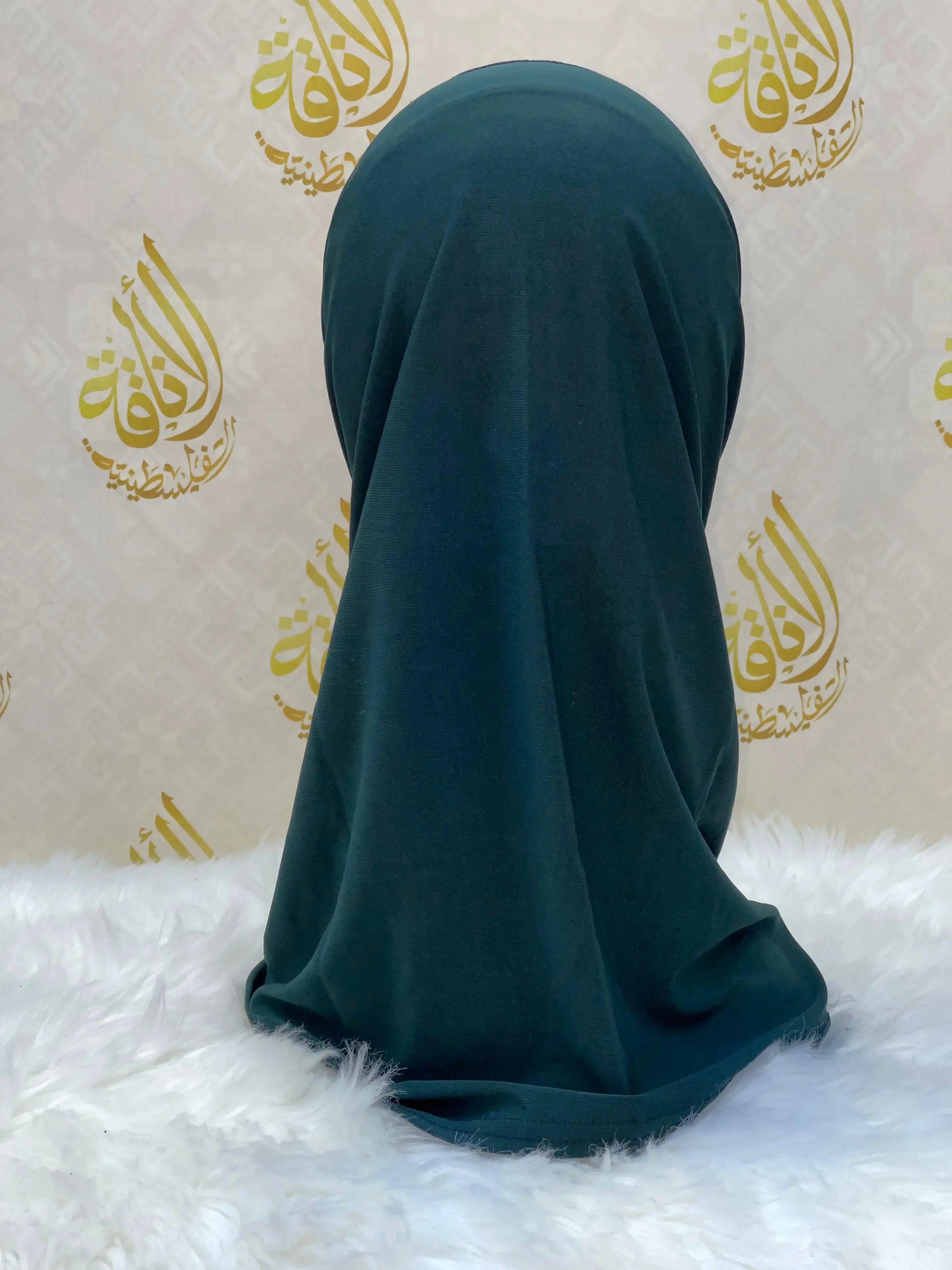 Dark green lycra hijab for women displayed on mannequin with Palestinian Elegance logo backdrop