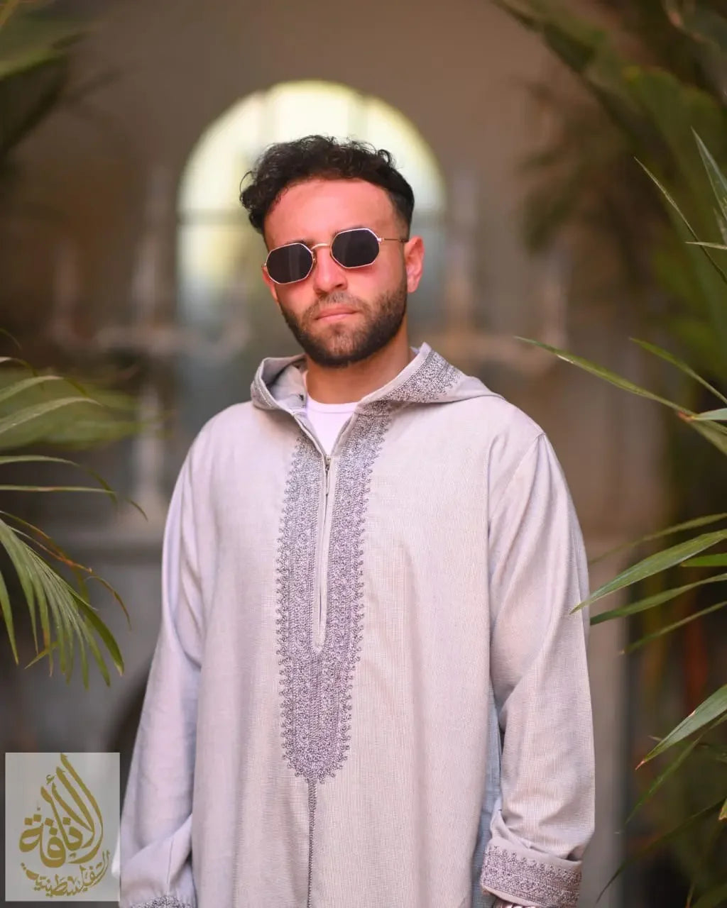 Moroccan jalabiya for men in light gray with intricate embroidery worn casually by a man with sunglasses