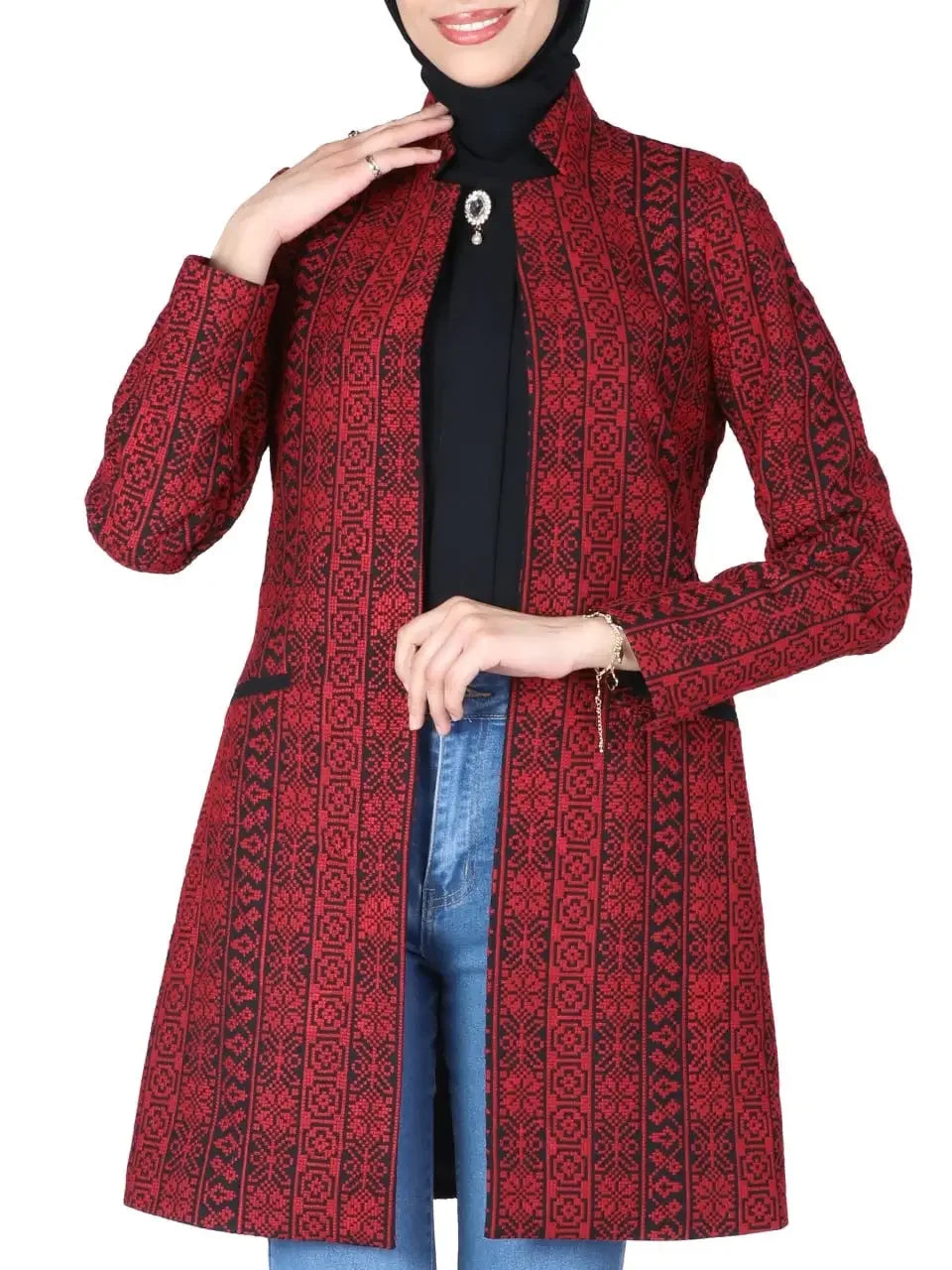 Red Palestinian embroidered jacket with traditional black geometric patterns worn over black top and jeans