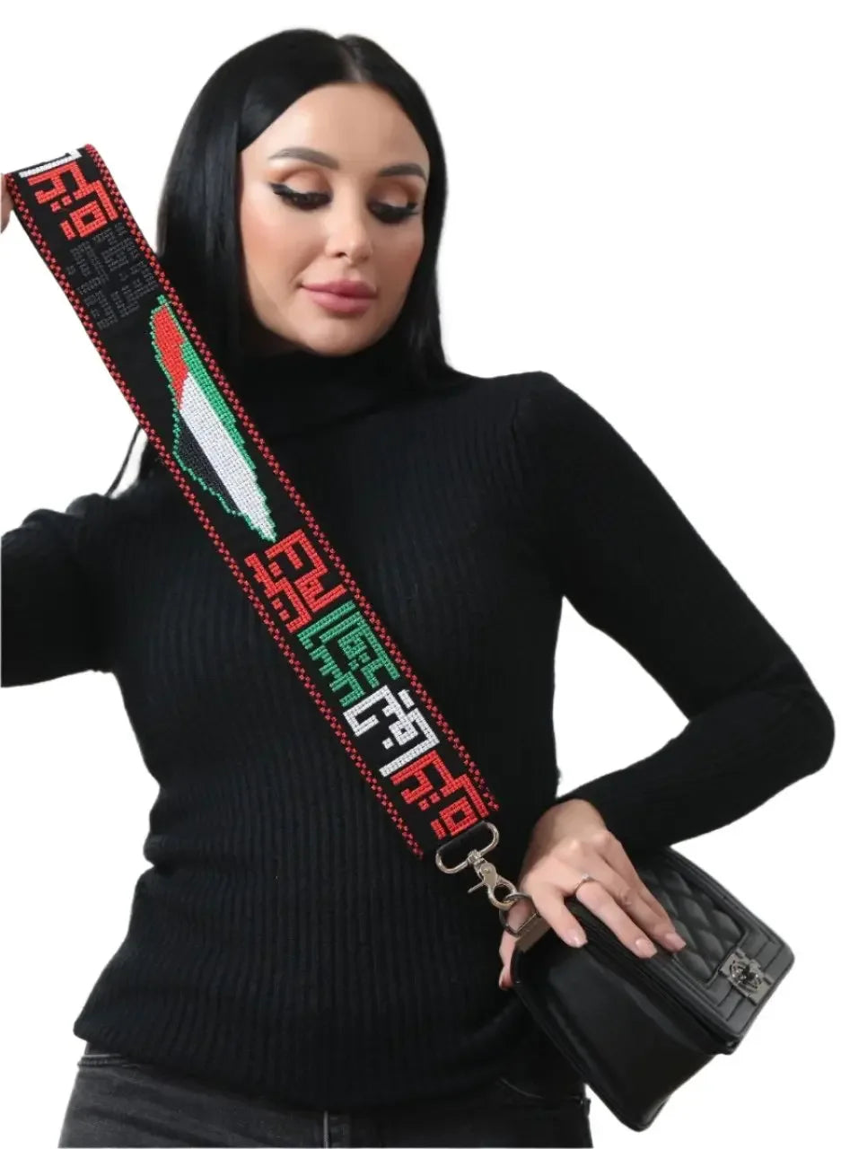 Palestinian embroidered purse strap in red, black, green, and white worn by woman holding black purse