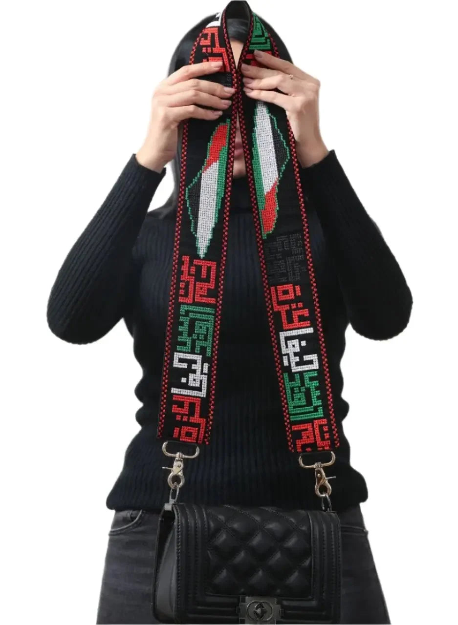 Palestinian embroidered purse strap with traditional red green and white geometric patterns attached to black quilted purse