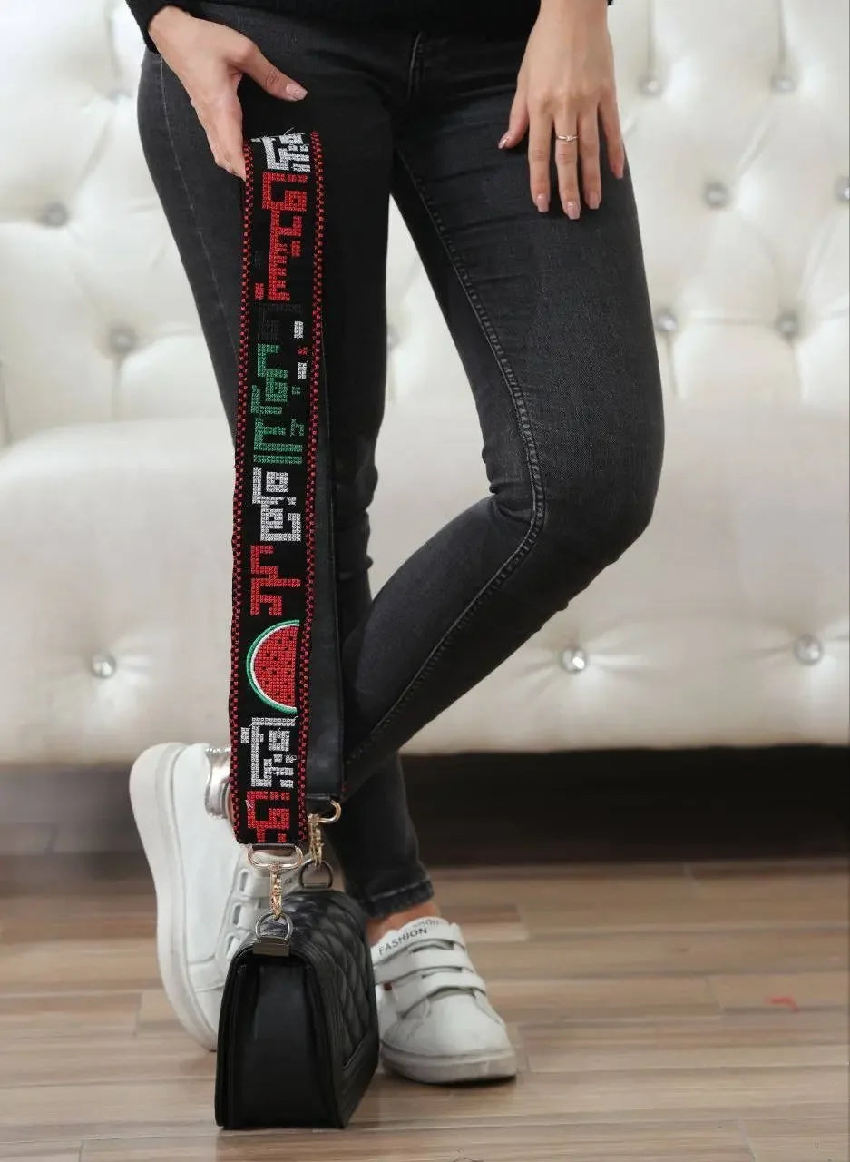 Palestinian embroidered purse strap with colorful traditional patterns attached to a black purse