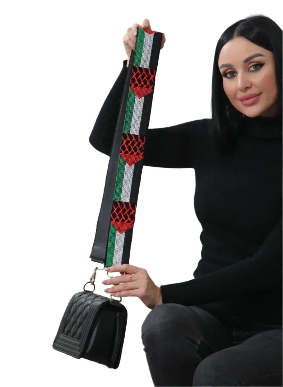 Palestinian embroidered purse strap with red and green embroidery held by woman with black handbag
