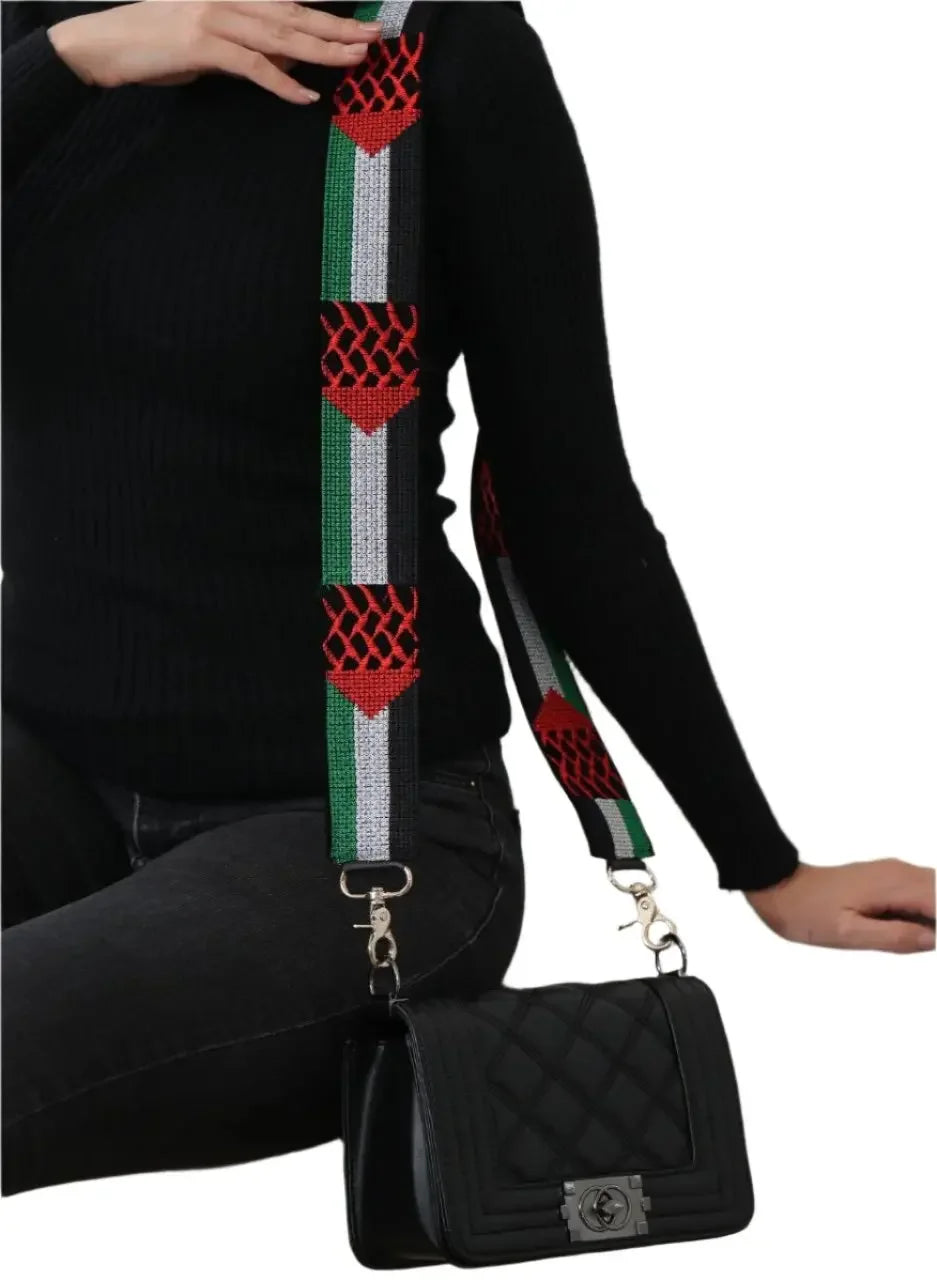 Palestinian embroidered purse strap with red, green, white, and black design attached to black quilted handbag