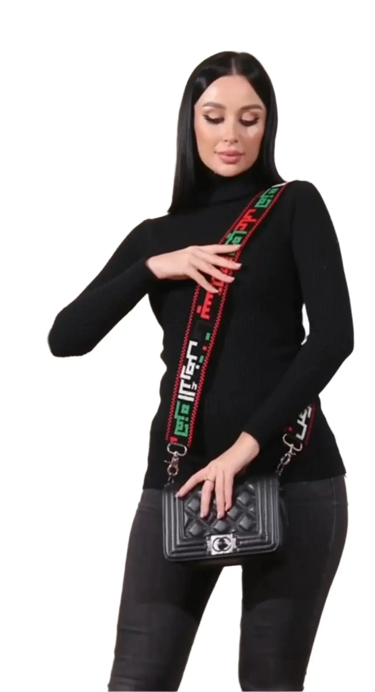 Woman wearing a black turtleneck with a Palestinian embroidered purse strap holding a black quilted purse
