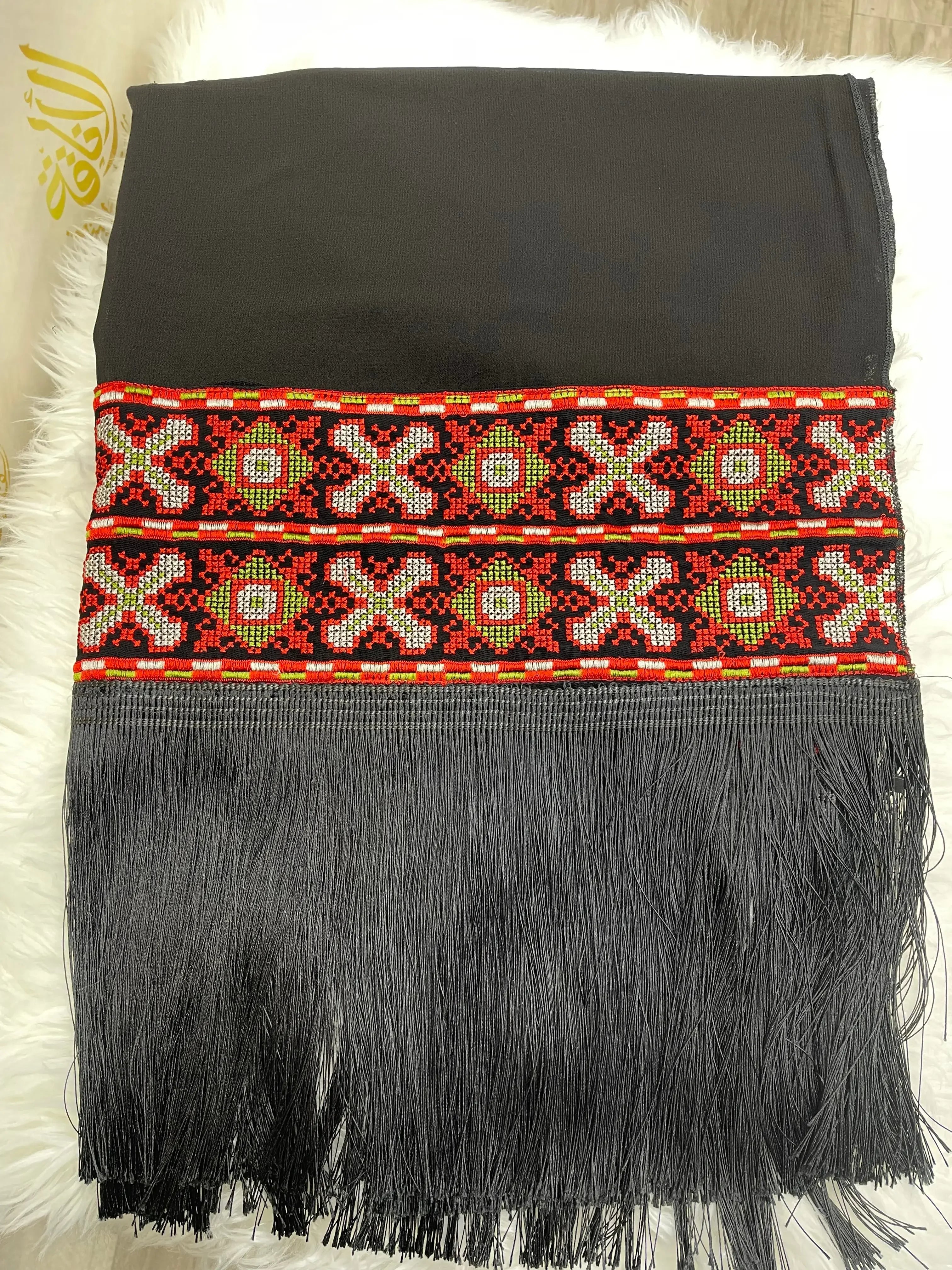 Palestinian embroidered shawl with intricate red and green geometric patterns and black fringe detailing