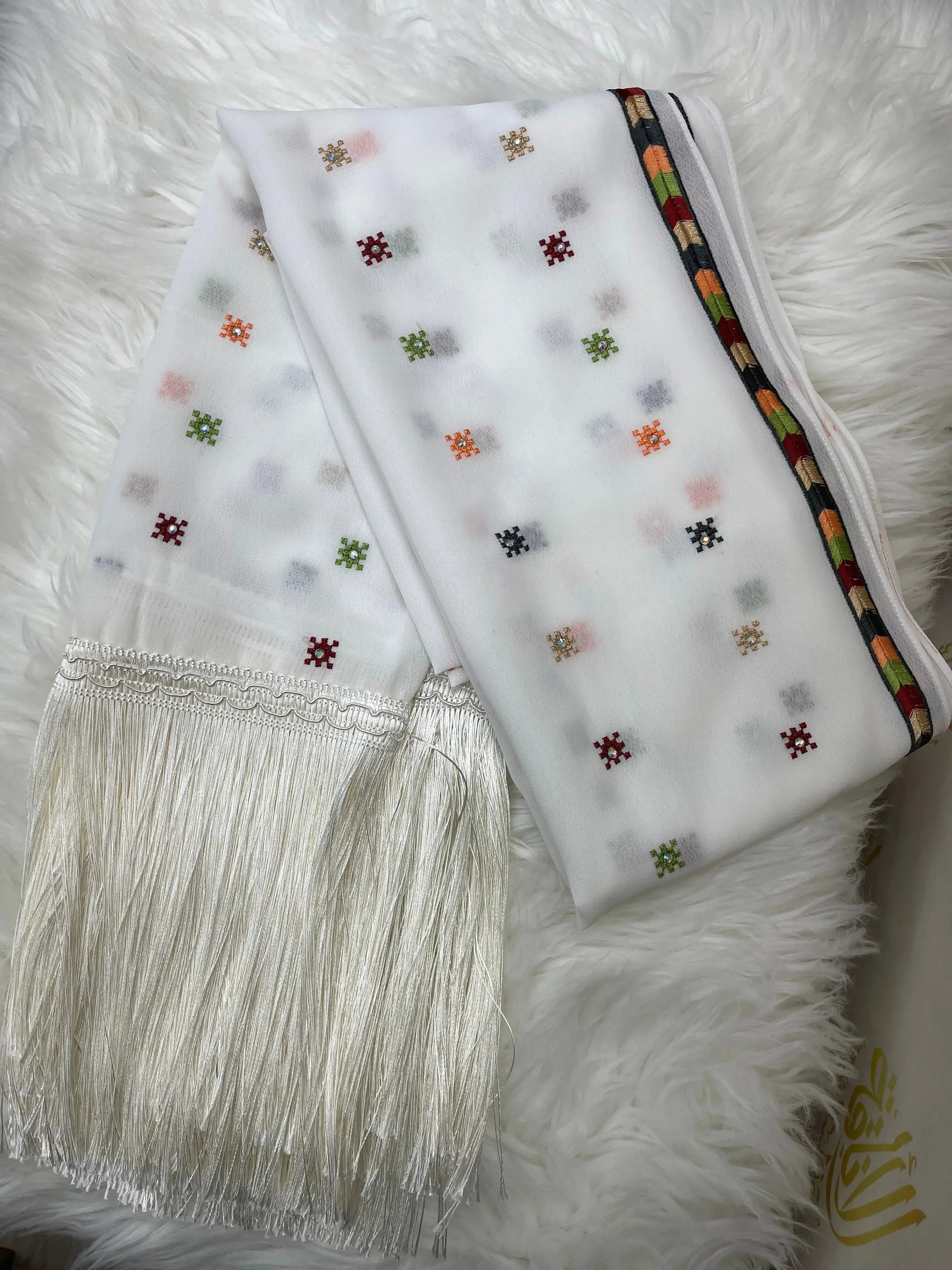 White Palestinian embroidered shawl with multicolor thread patterns and fringe detailing from Palestinian Elegance
