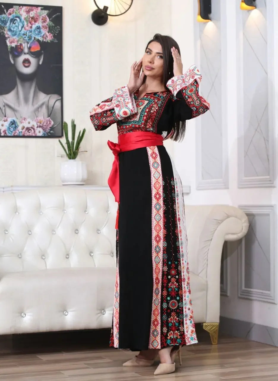 Woman wearing a Palestinian embroidered thobe with colorful traditional patterns and red sash by Palestinian Elegance