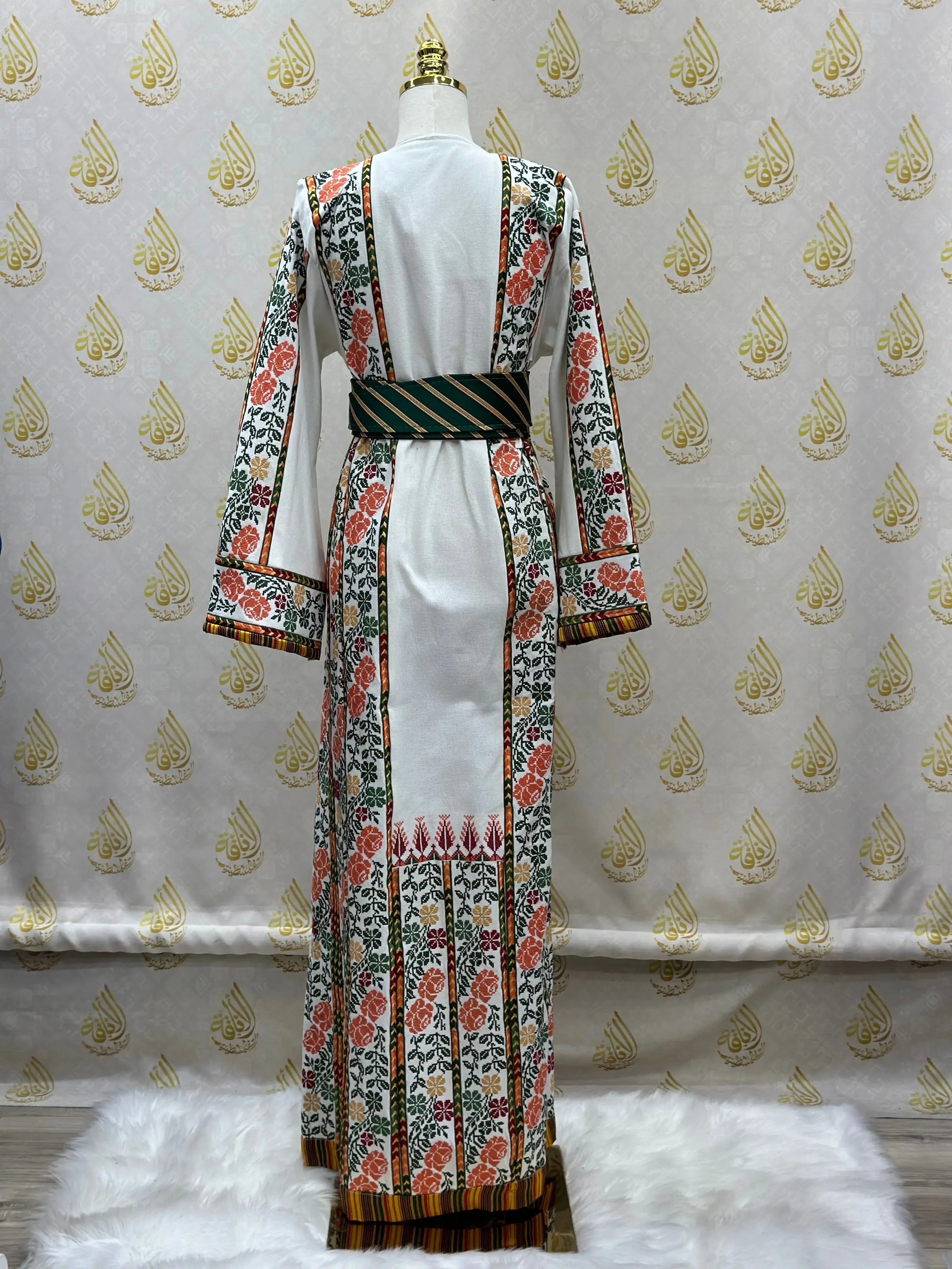 Palestinian embroidered thobe with floral patterns and wide sleeves displayed on mannequin