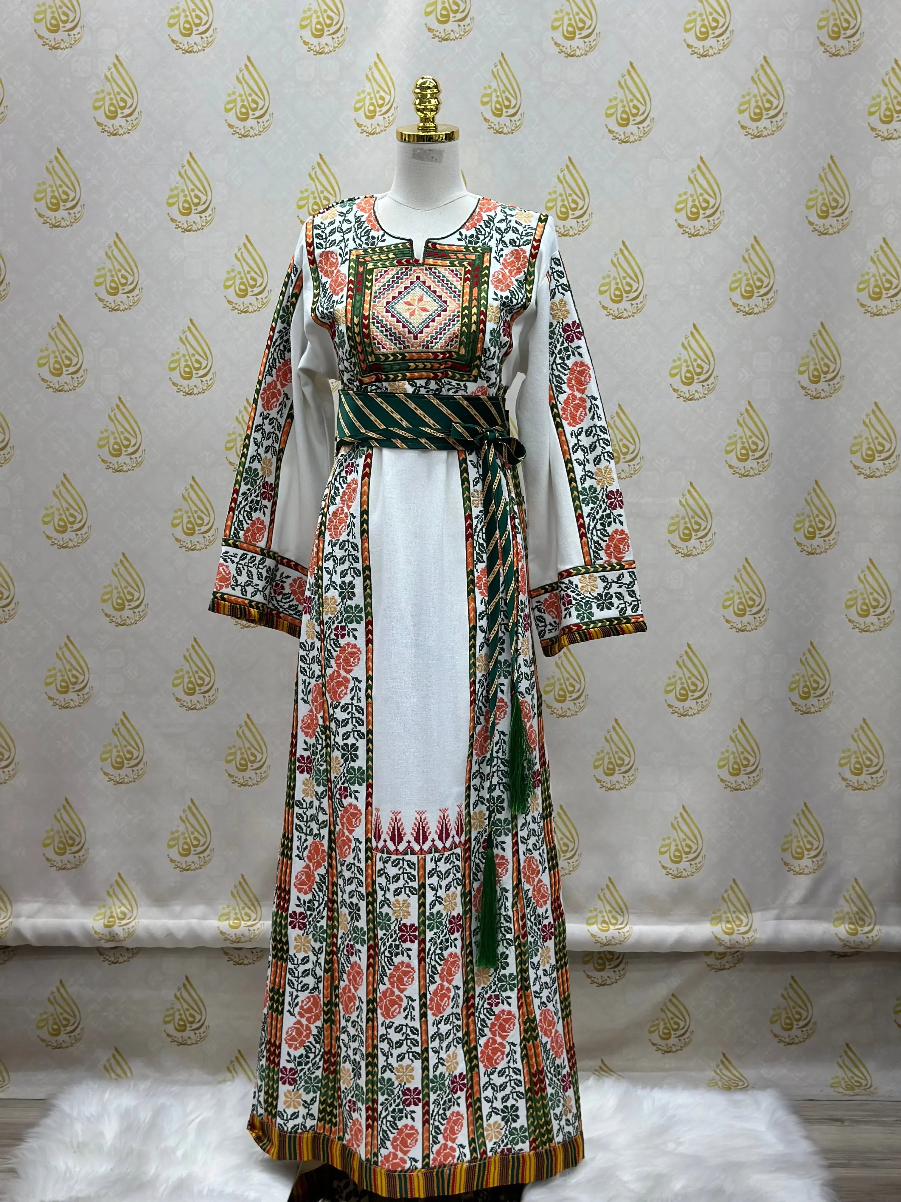 Palestinian embroidered thobe with intricate floral and geometric patterns in red, green, and black on white fabric