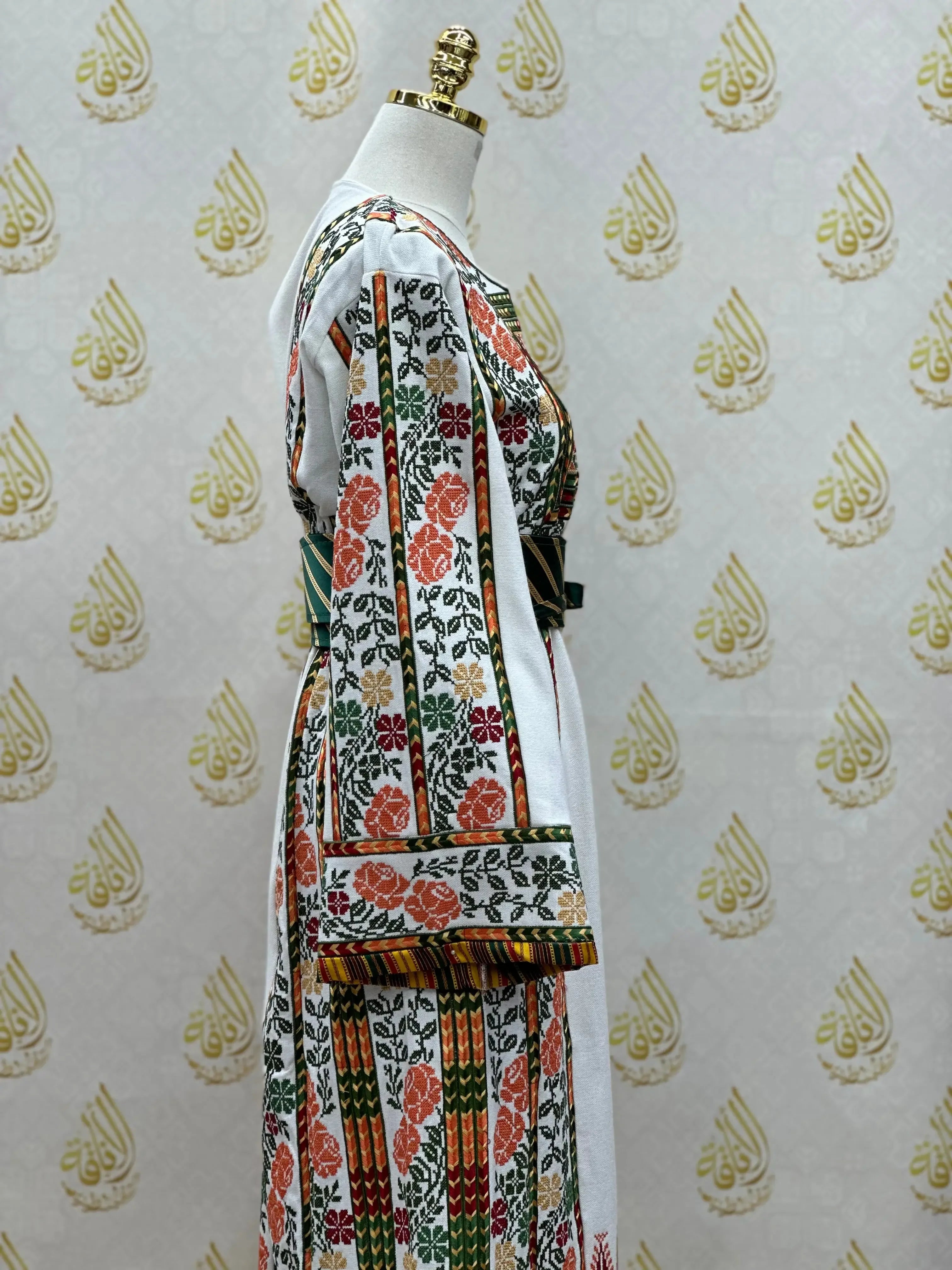 Palestinian embroidered thobe with colorful floral and geometric designs displayed on a mannequin by Palestinian Elegance
