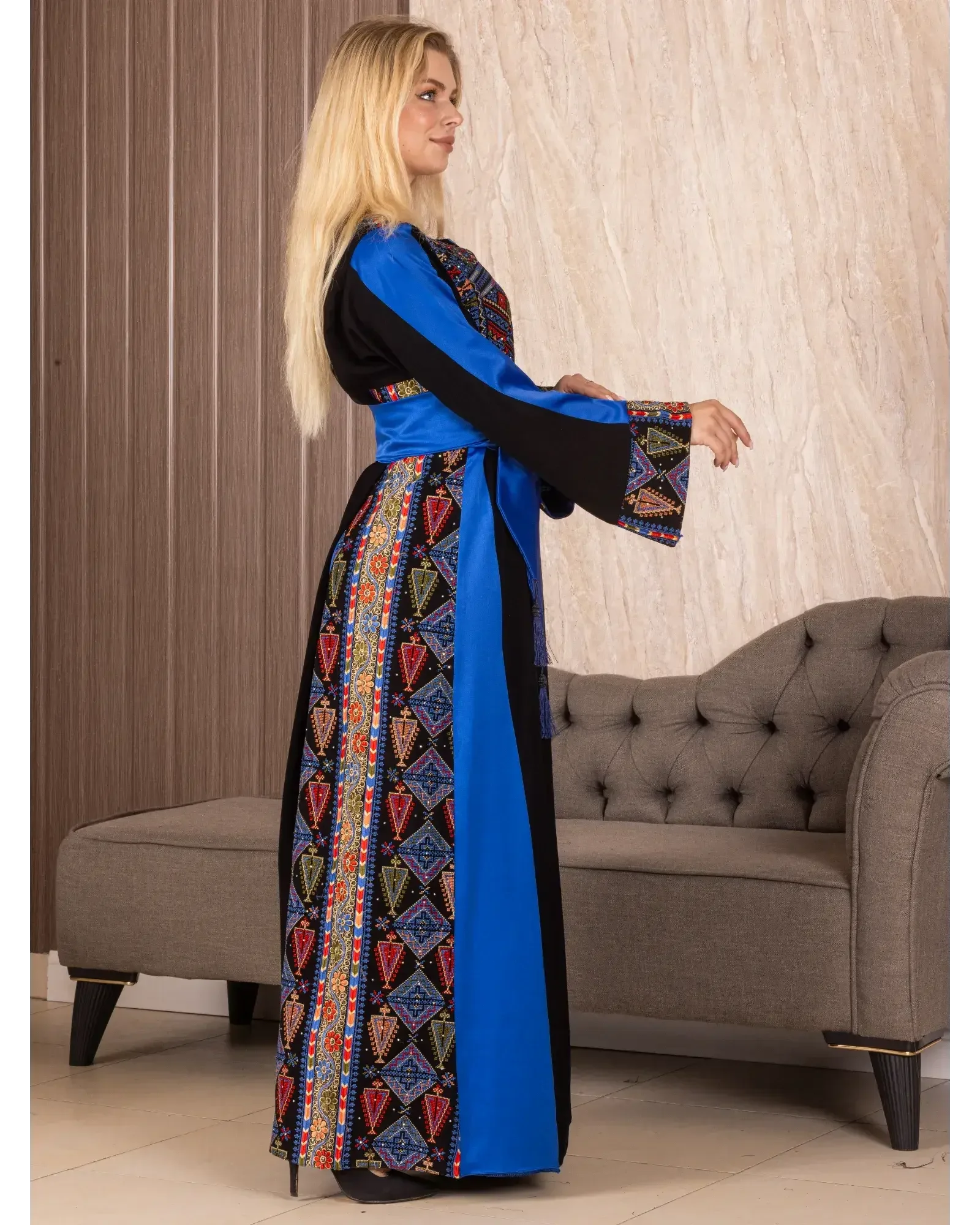 Woman wearing a Palestinian embroidered thoub with colorful geometric patterns and blue accents