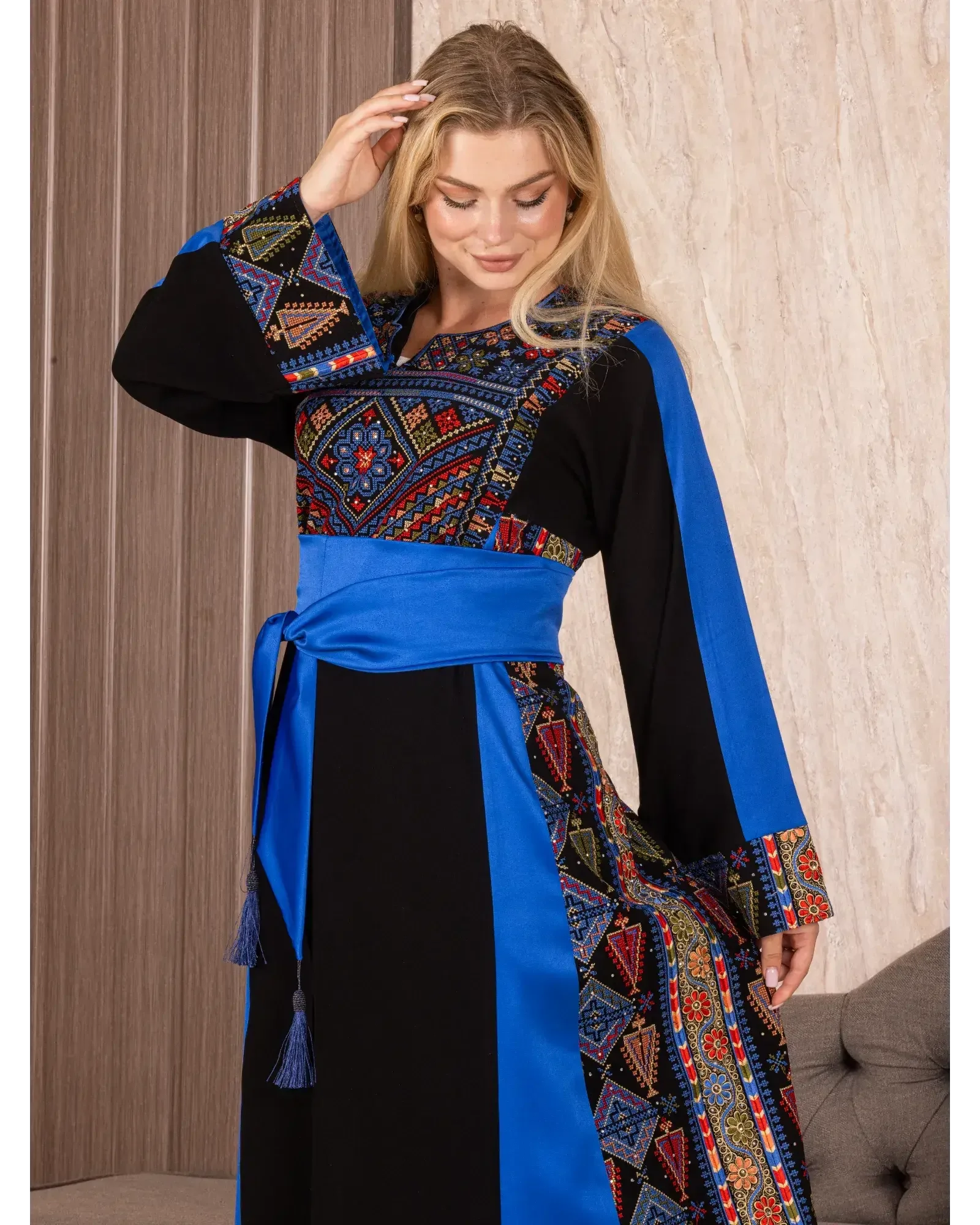 Palestinian embroidered thoub with vibrant geometric patterns and blue sash worn by woman