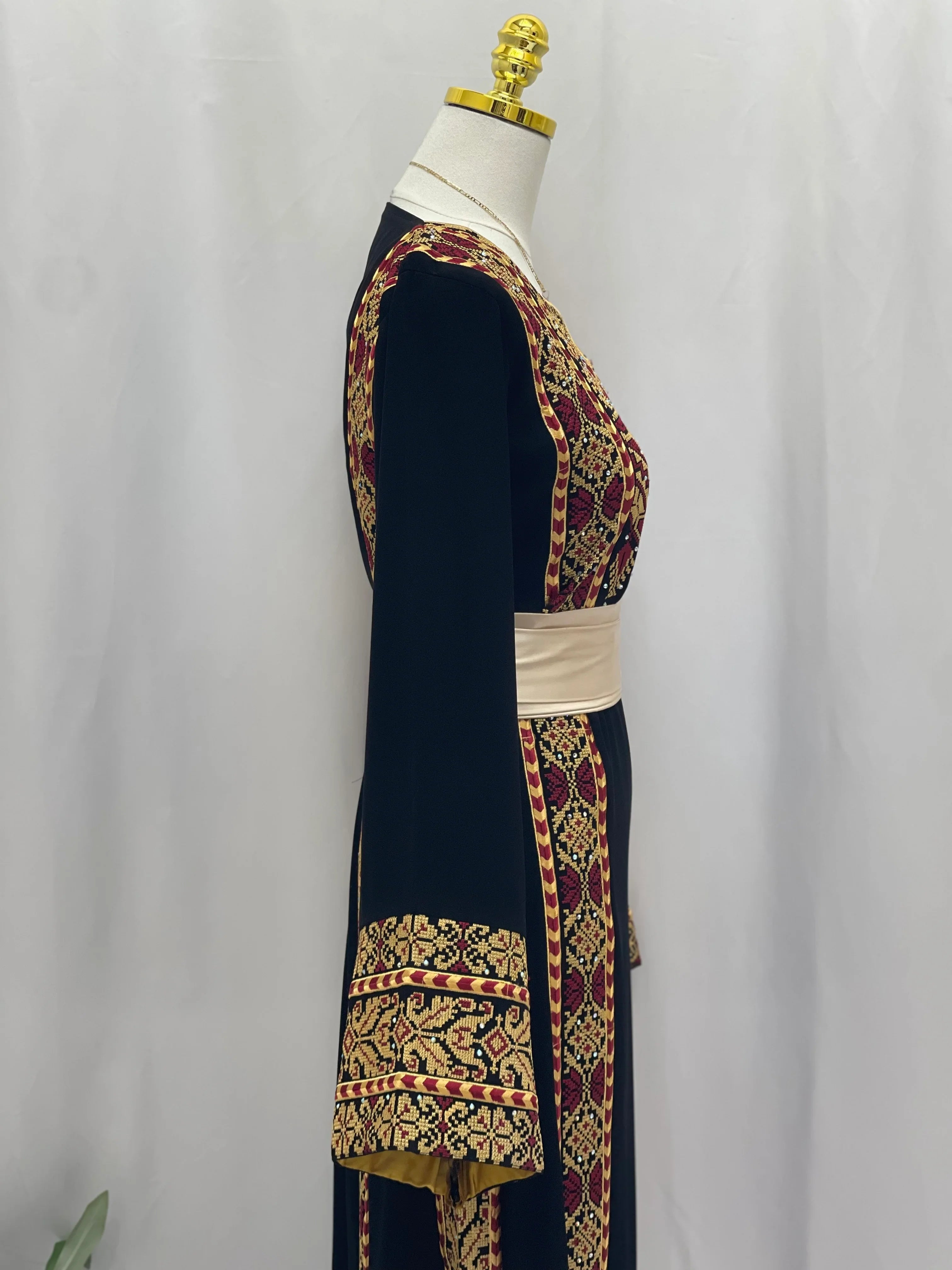 Palestinian embroidered thoub with intricate red and gold embroidery from Palestinian Elegance on mannequin