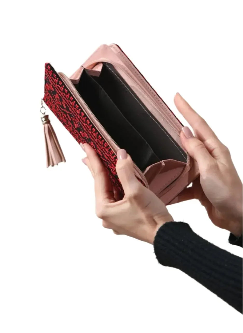 Palestinian embroidered wallet with red and black stitching held open showing multiple compartments