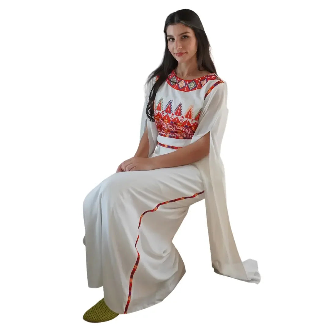Elegant white Palestinian embroidery dress with colorful red and orange traditional patterns worn by seated woman