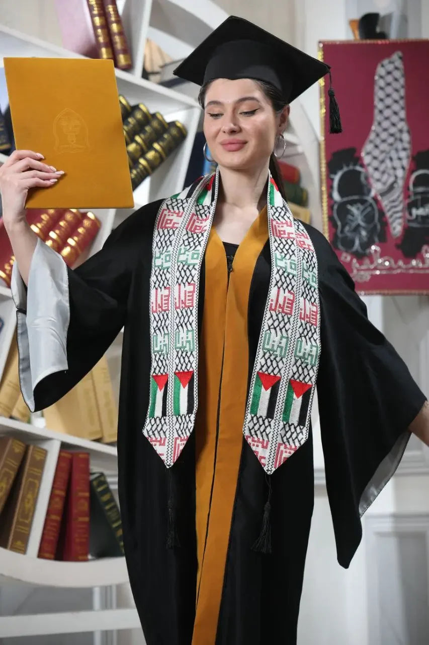 Graduate wearing a Palestinian graduation stole with traditional embroidery and flags over a black gown and cap