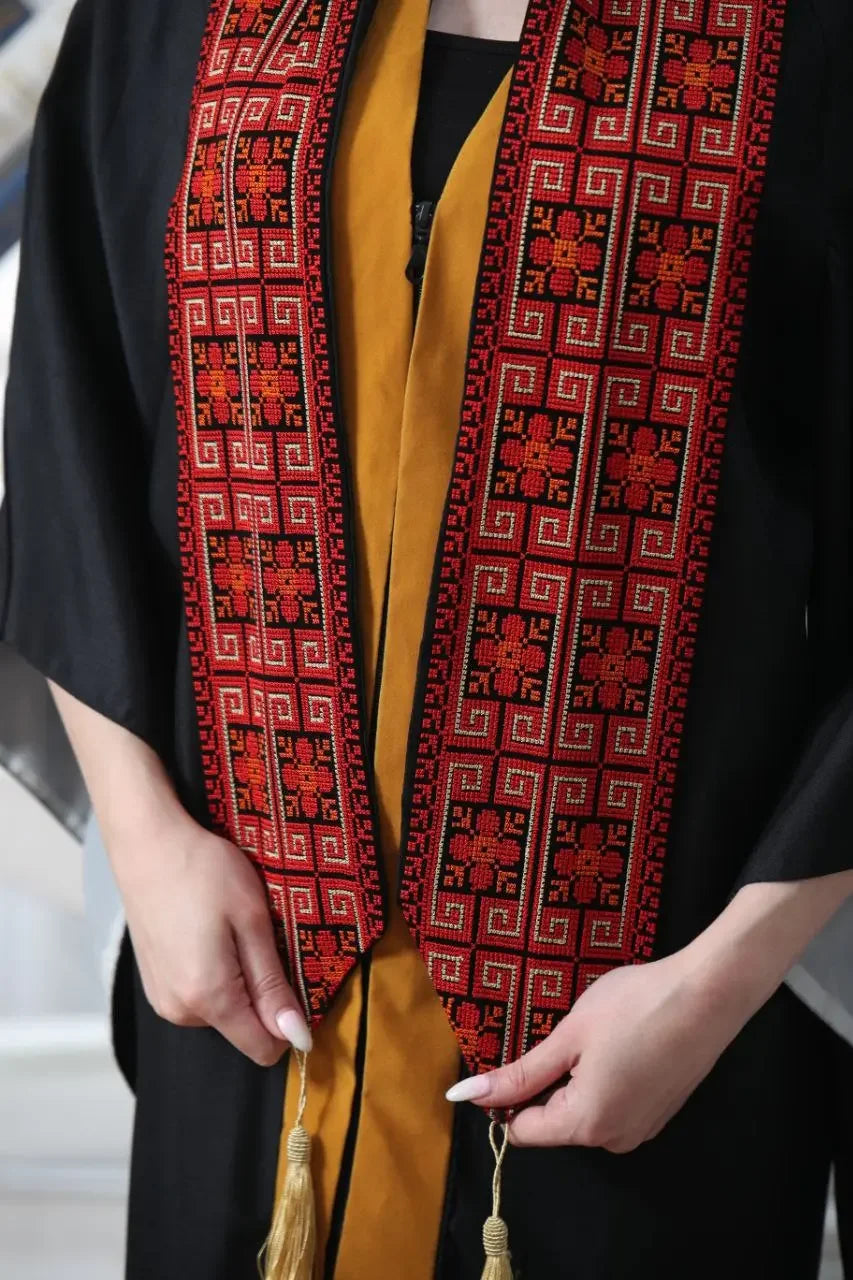 Palestinian graduation stole with intricate red and black embroidery worn over graduation gown
