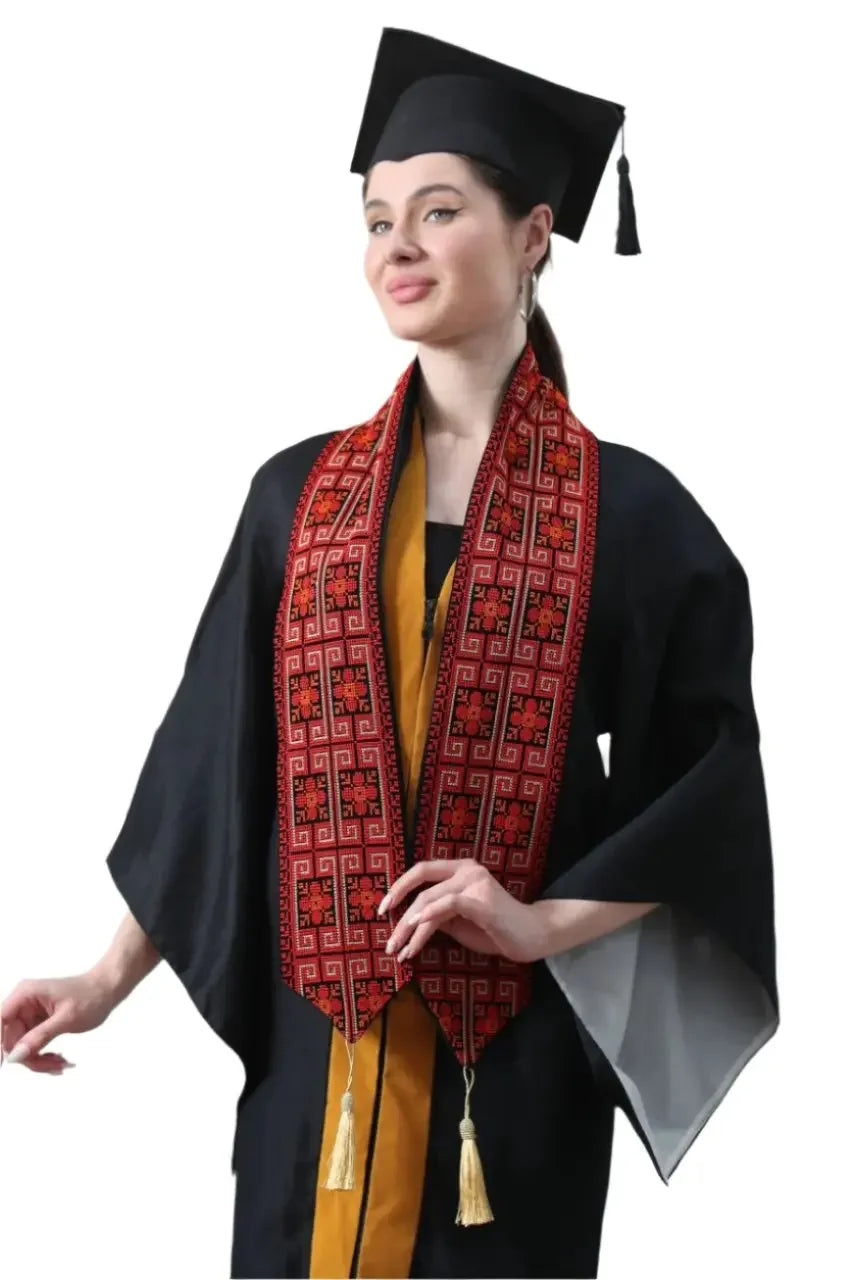 Woman wearing a Palestinian graduation stole with traditional embroidery and tassels over black graduation gown and cap