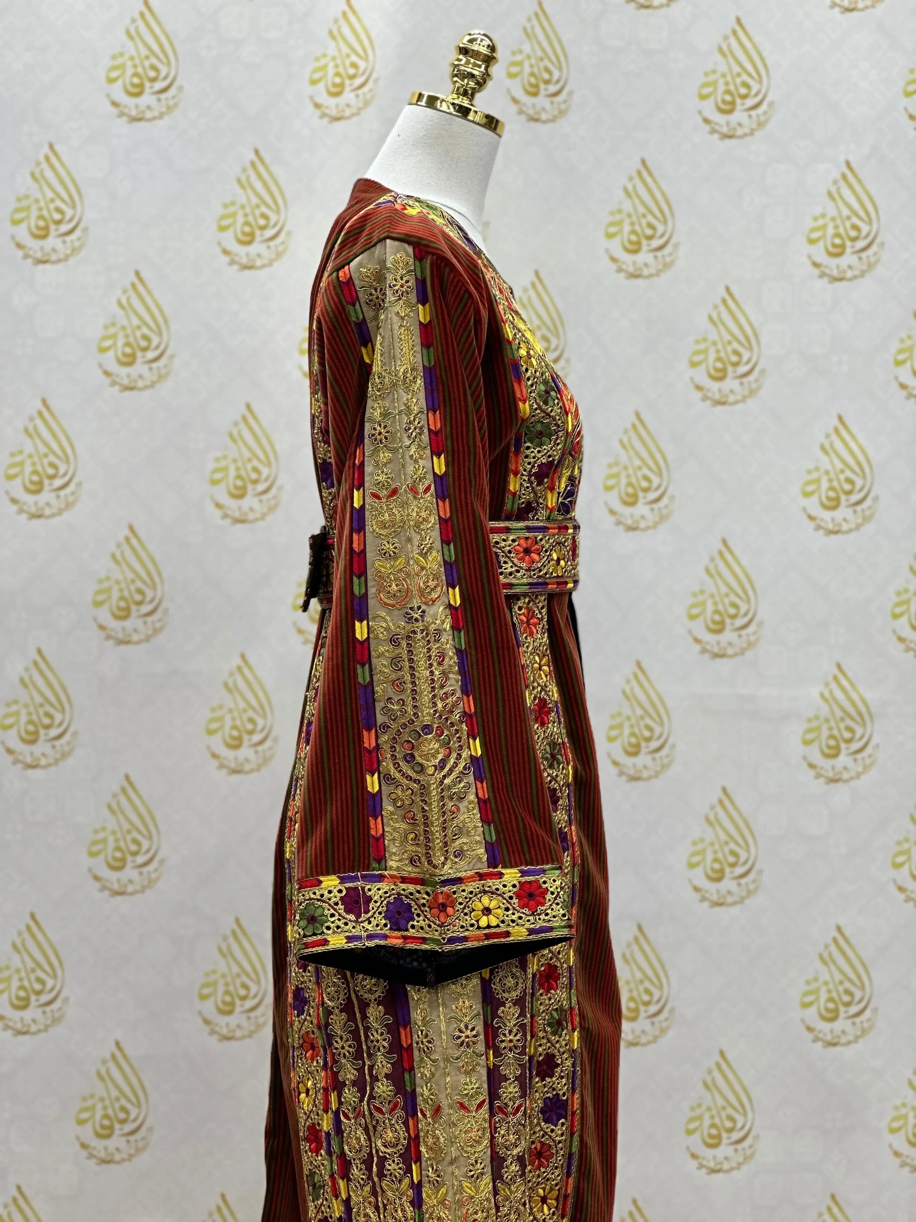 Palestinian thoub dress with intricate gold and colorful embroidery on rich maroon fabric by Palestinian Elegance