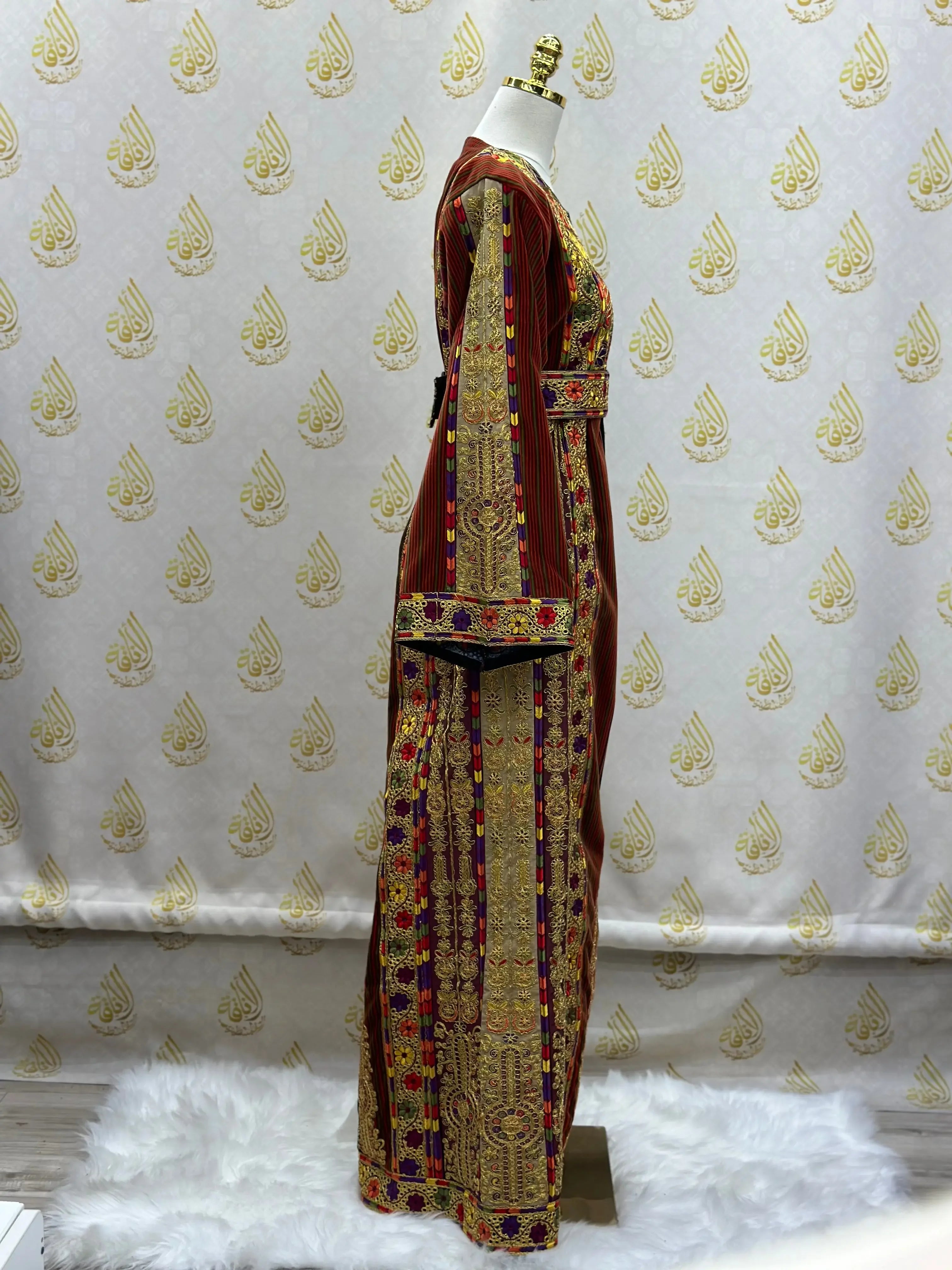 Palestinian thoub dress with intricate gold and red embroidery displayed on a mannequin by Palestinian Elegance