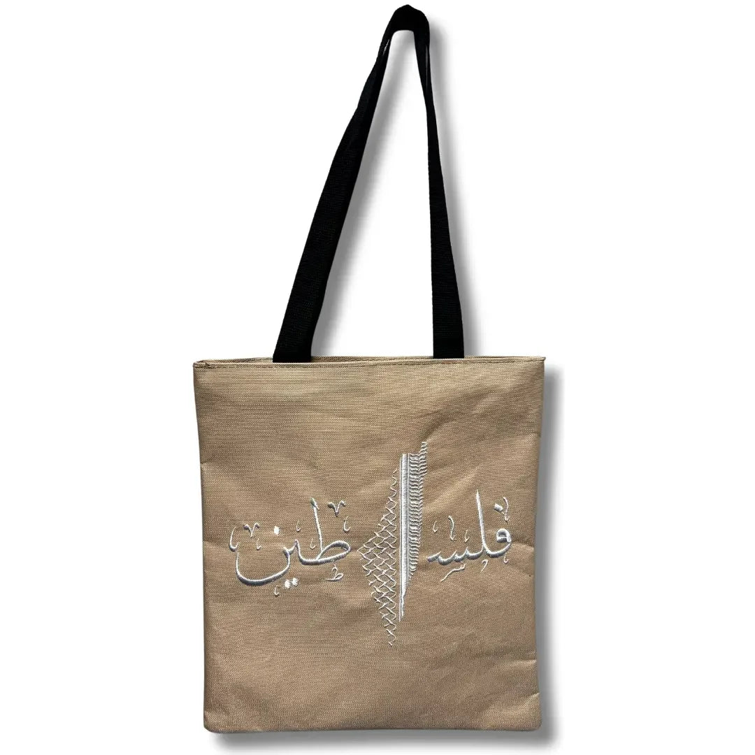 Beige Palestinian tote bag with black handles and white Arabic embroidery design