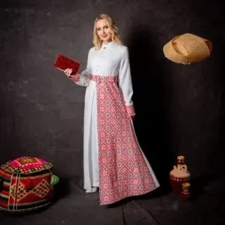 Woman wearing an embroidered Palestinian dress with traditional red and white patterns holding a red clutch