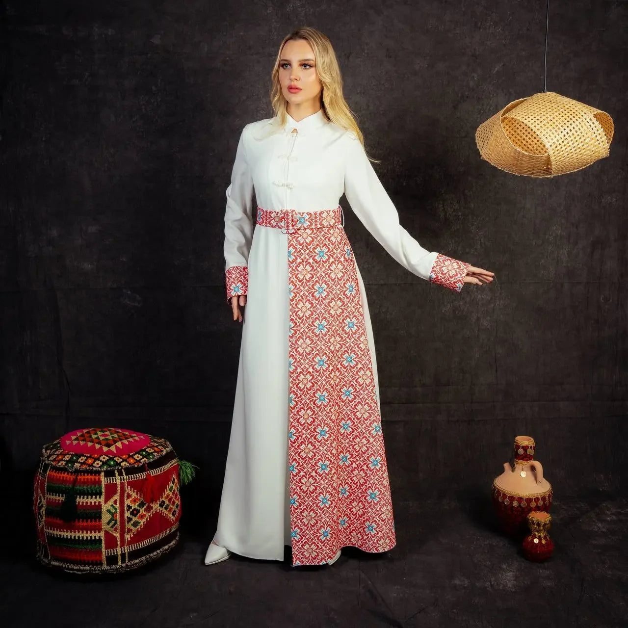 Woman wearing an embroidered Palestinian dress with white and red traditional patterns by Palestinian Elegance