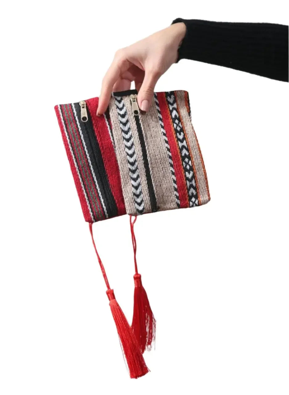 Hand holding a colorful Palestinian wool wallet with traditional patterns and red tassels
