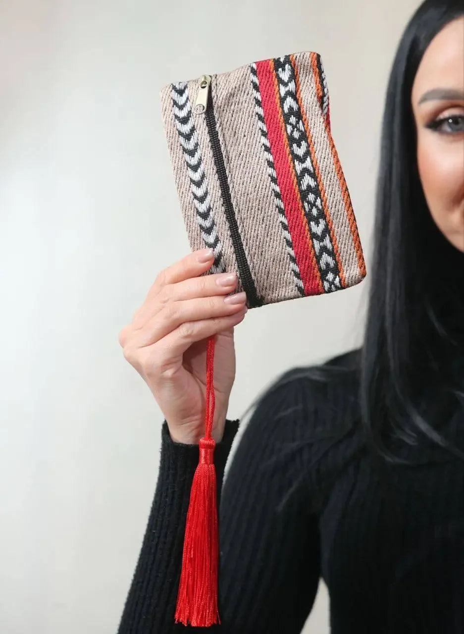 Palestinian wool wallet with traditional patterns and red tassel held by a woman in black sweater