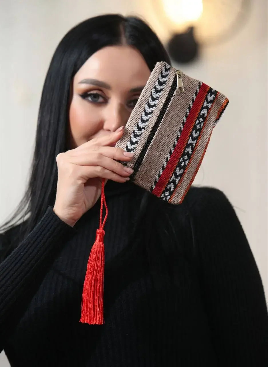 Palestinian wool wallet with colorful traditional patterns and red tassel held by woman