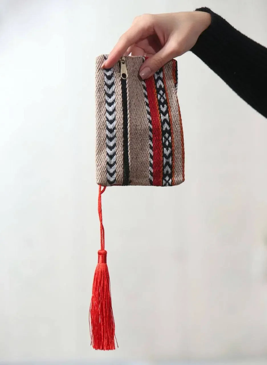 Palestinian wool wallet with traditional patterns and red tassel held by hand from Palestinian Elegance