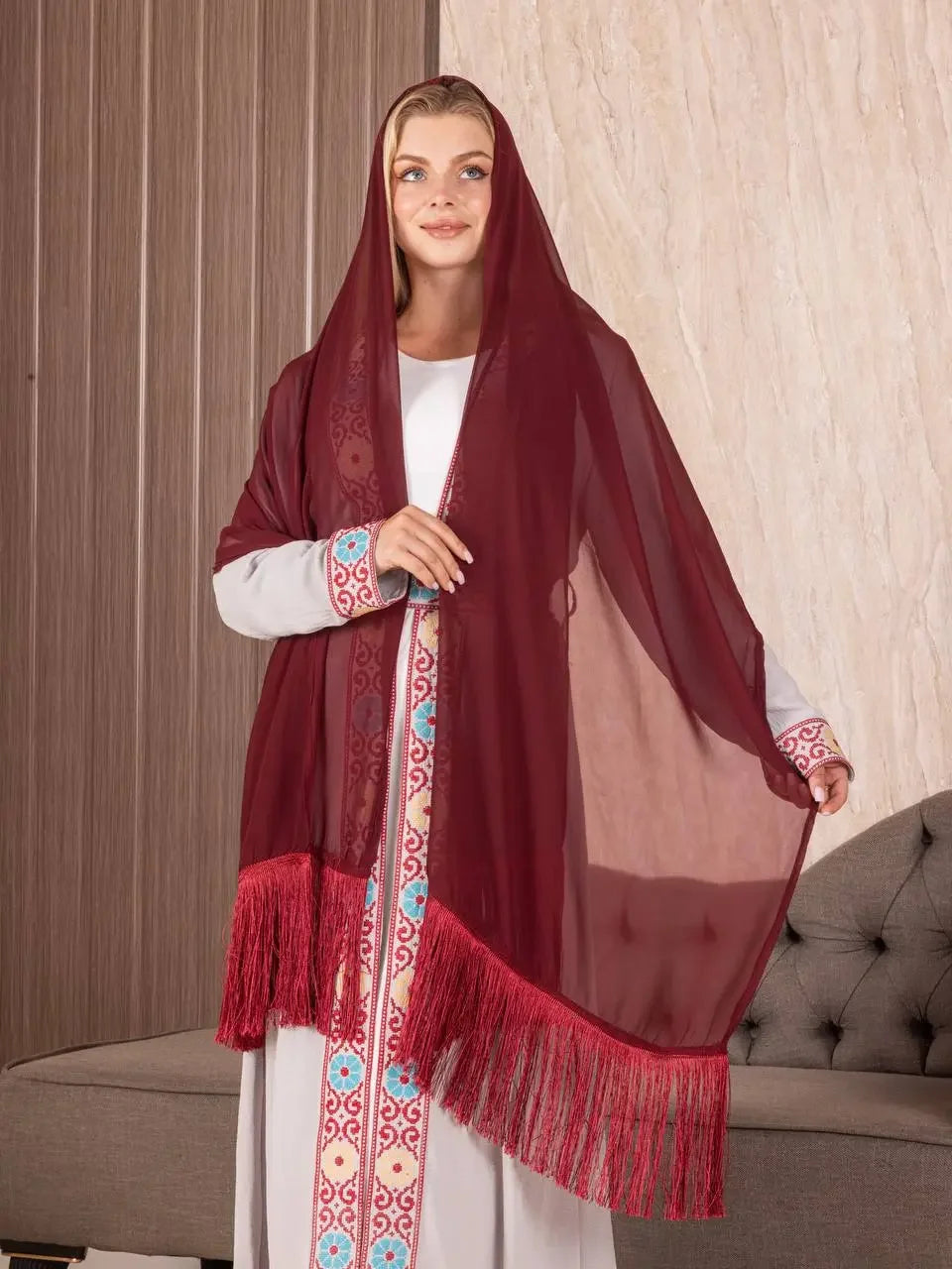 Traditional Palestinian khirka shawl in deep red with intricate embroidery and fringe detailing worn by woman
