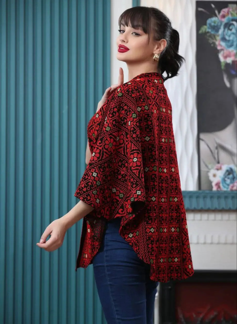 Woman wearing Palestinian embroidered cape with traditional red and black patterns casual style