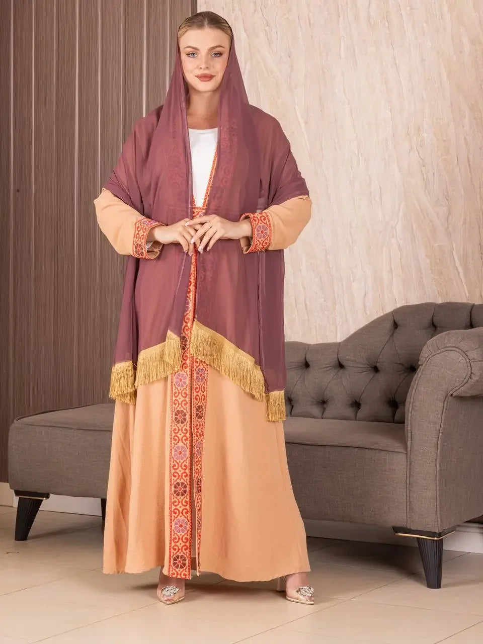 Traditional Palestinian khirka shawl in purple with gold fringe worn over peach embroidered dress