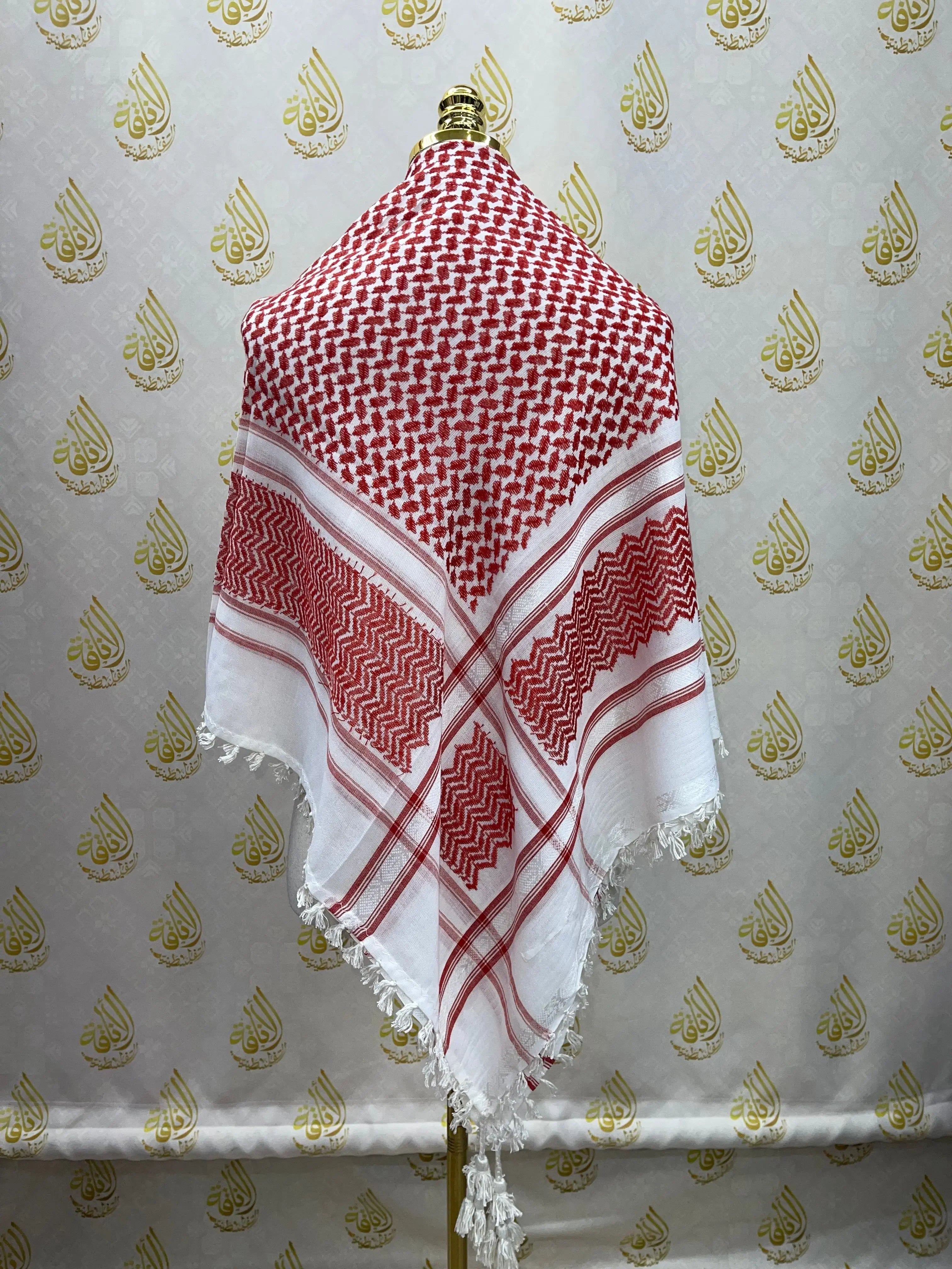 Red and white kuffiyeh scarf displayed on a mannequin with intricate traditional patterns
