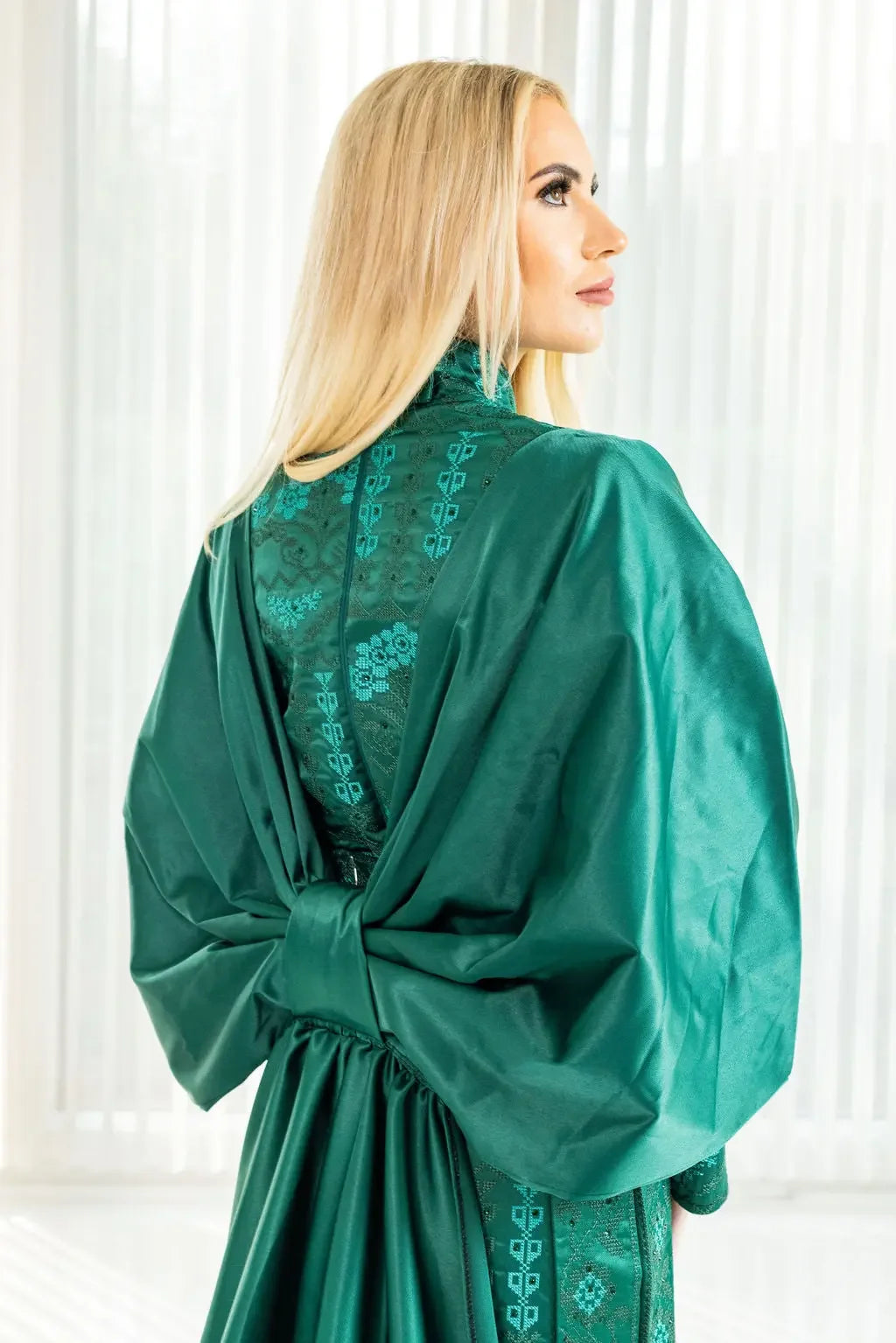 Satin bridal dress with cape in emerald green featuring intricate embroidery by Palestinian Elegance
