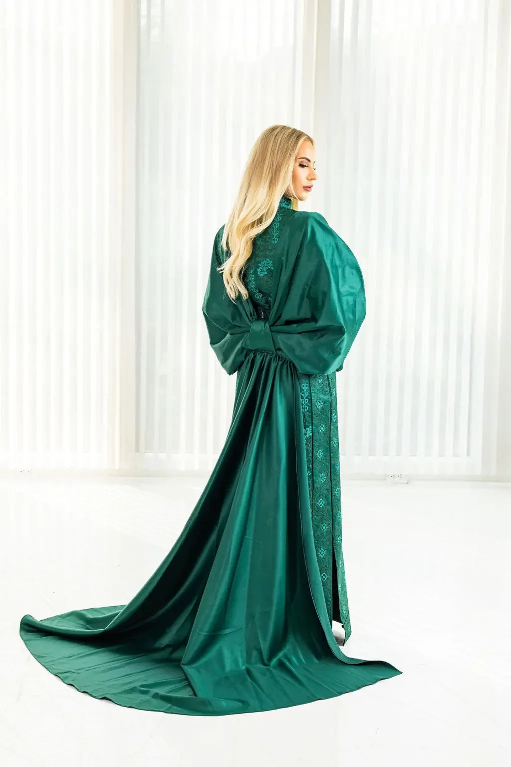 Green satin bridal dress with cape featuring intricate Palestinian Elegance embroidery on the back and sleeves