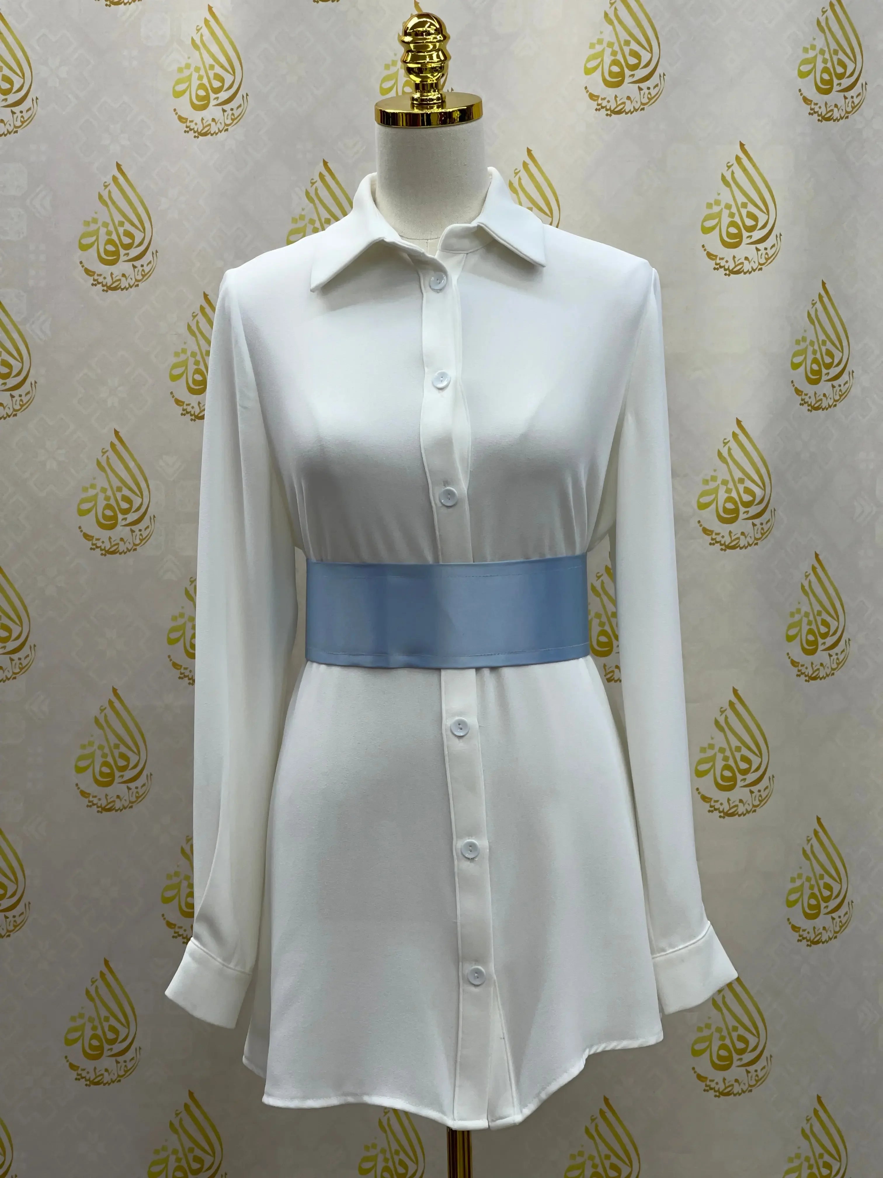 Palestinian Elegance satin waist belt in light blue worn over white button-down dress
