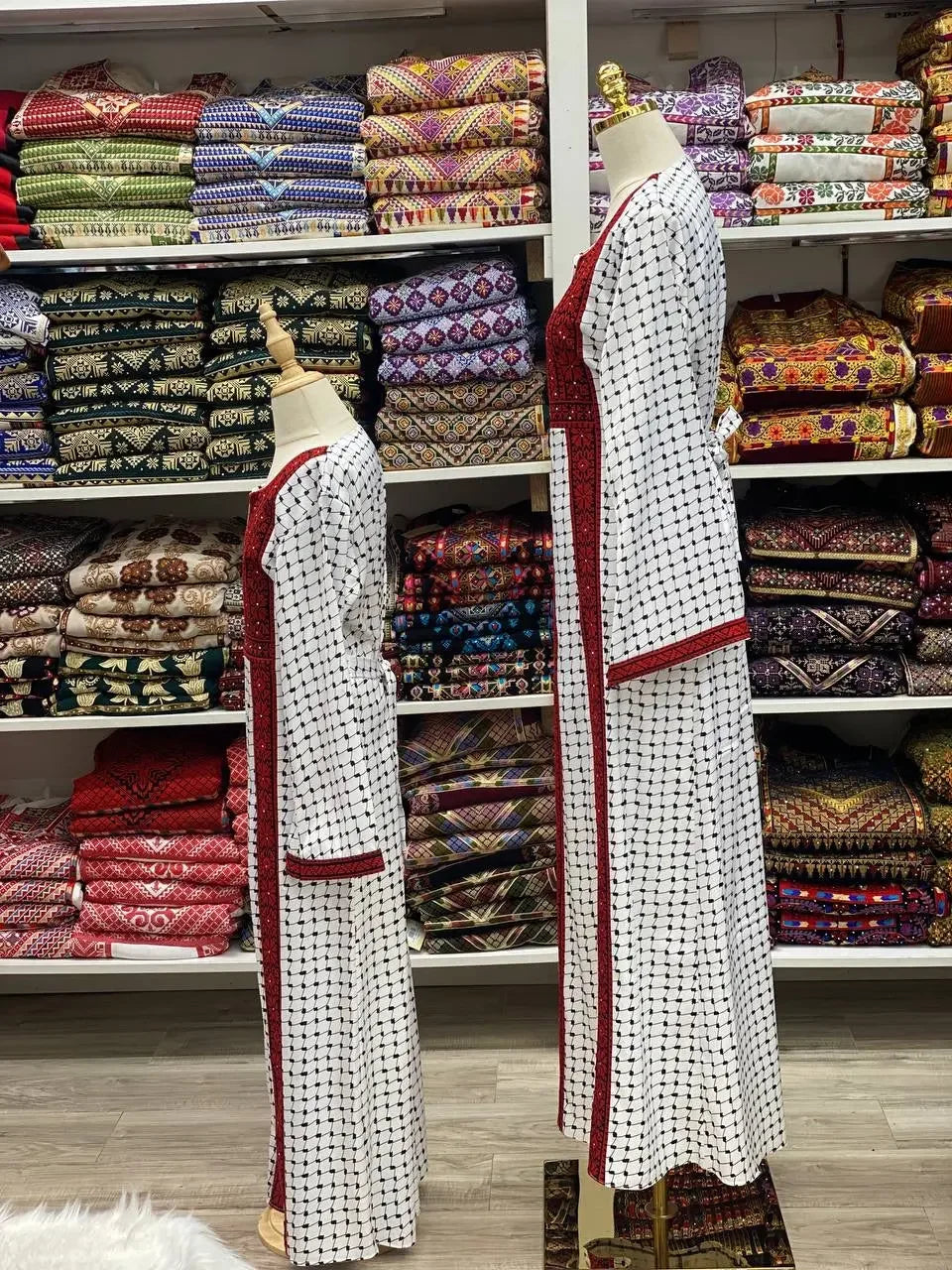 Palestinian Elegance embroidered teen girl abaya dress displayed on mannequins with patterned fabric background