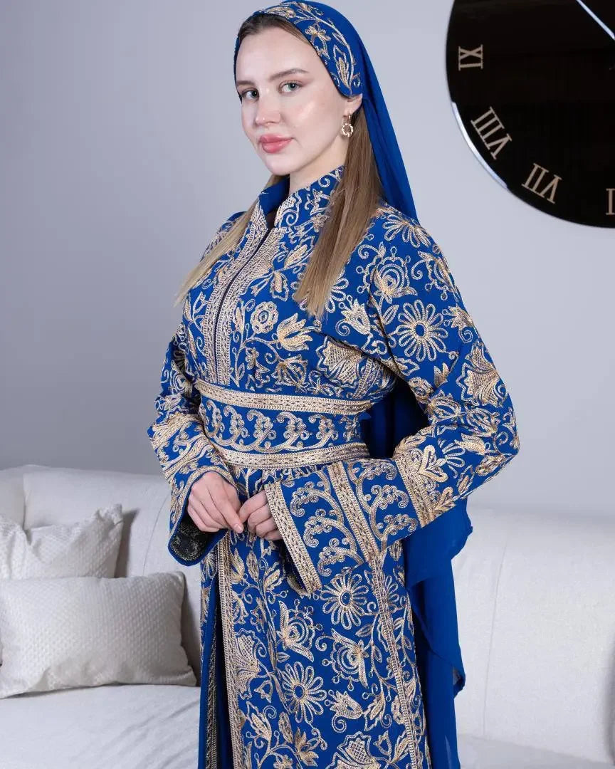 Woman wearing blue traditional embroidered kaftan with intricate gold floral patterns and matching headscarf